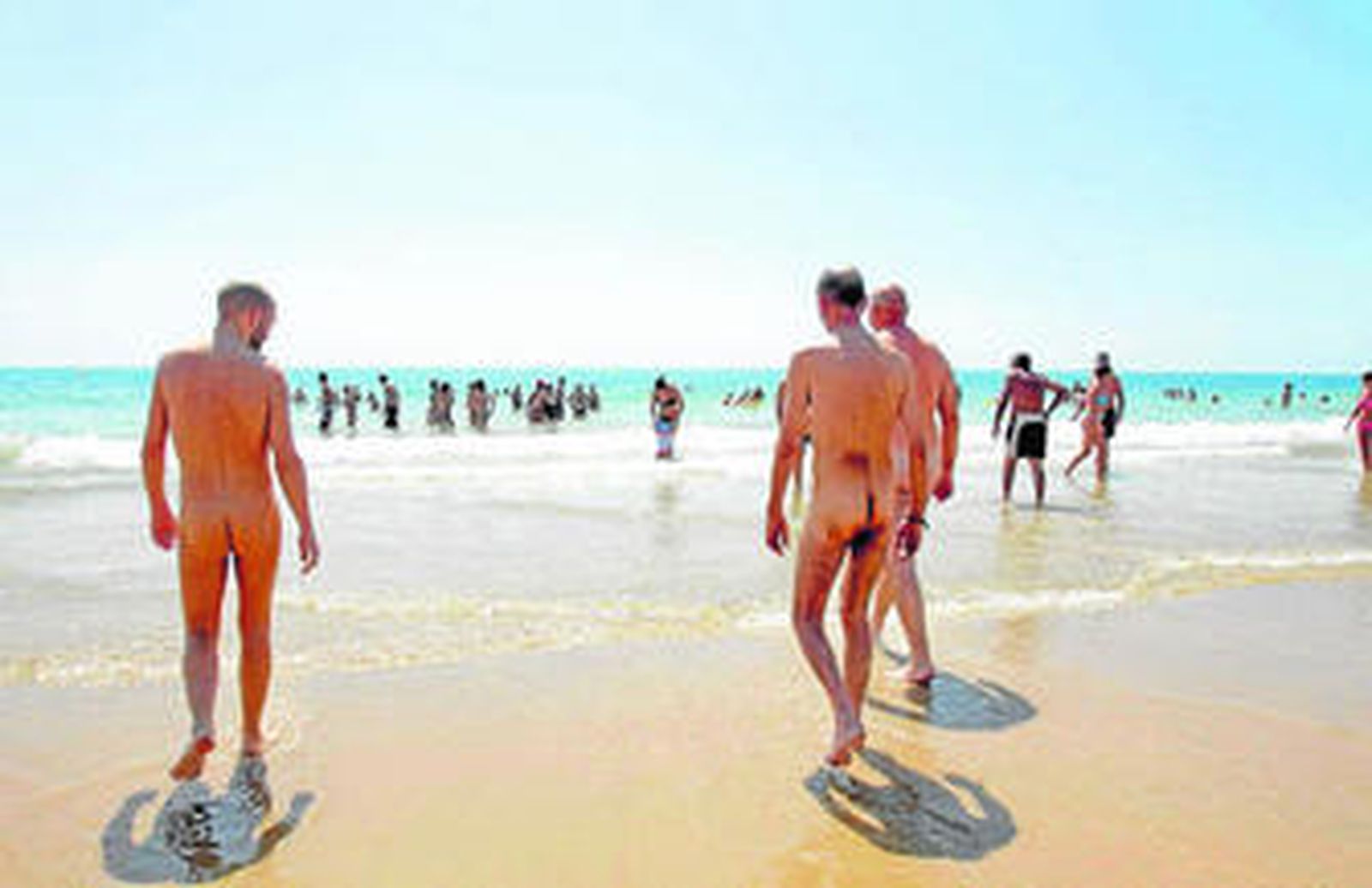 Turistas no textiles recorren la playa de Vera aprovechándose del sol y del agua.