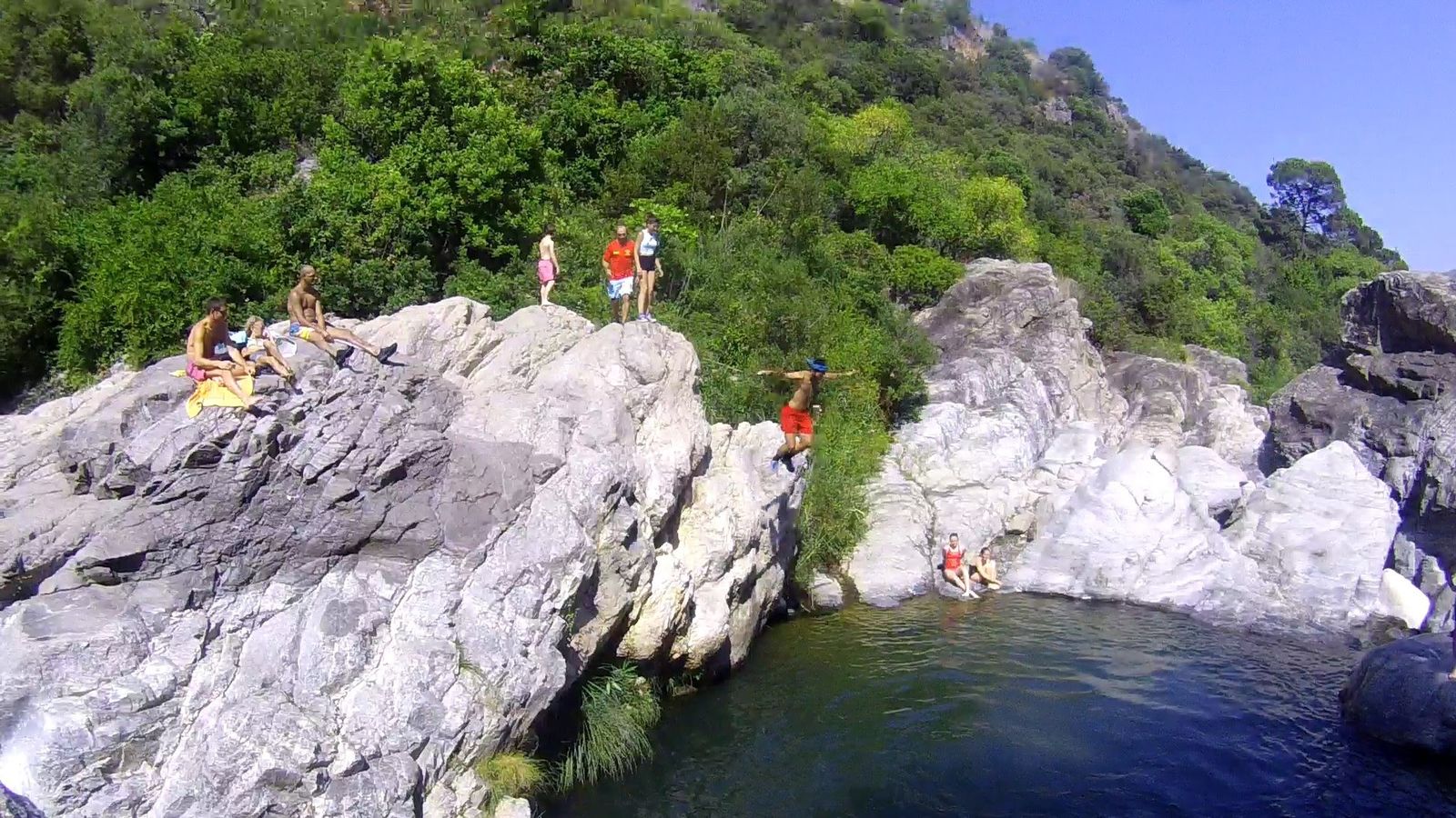 Varia personas saltan a una de las pozas del río Guadalmina.