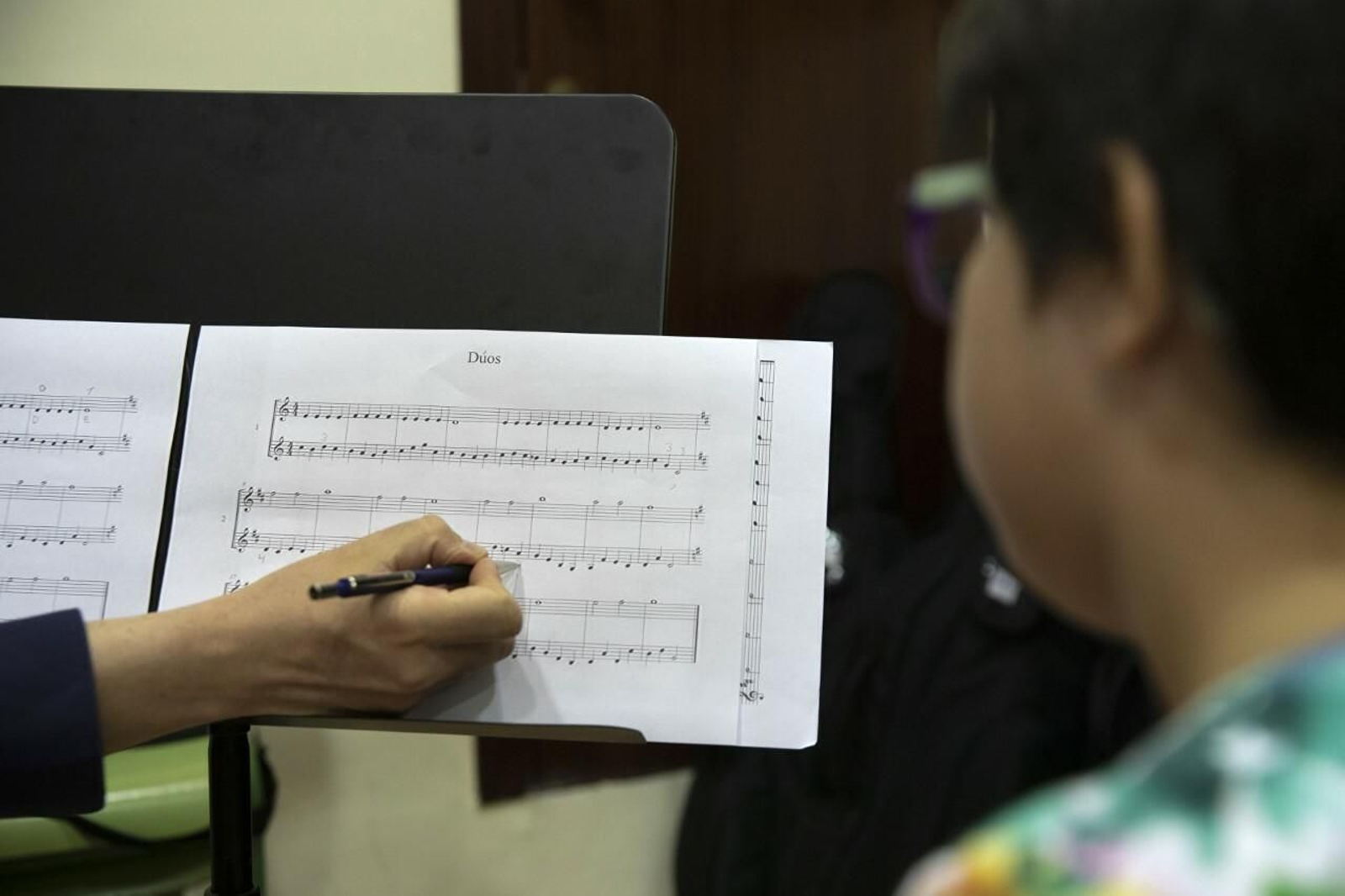 Un maestro enseña una partitura a un alumno.