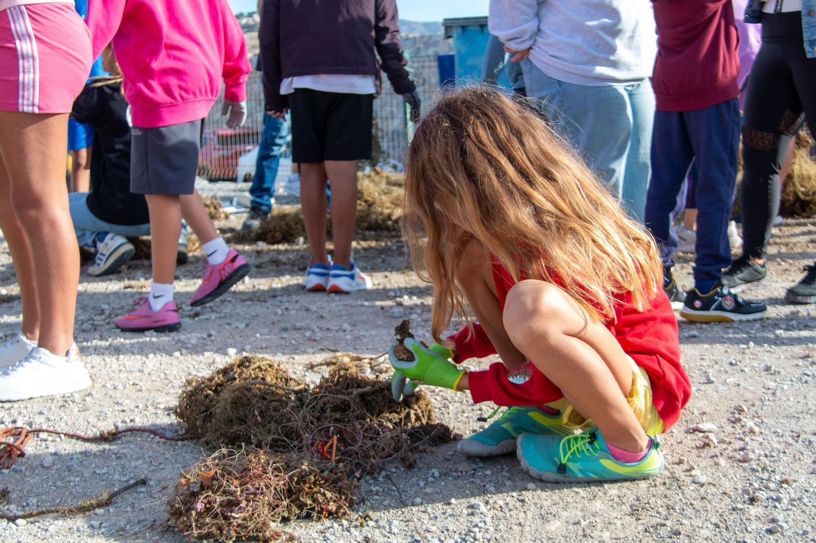 Una niña observa un trozo de coral sacado entre desechos marinos