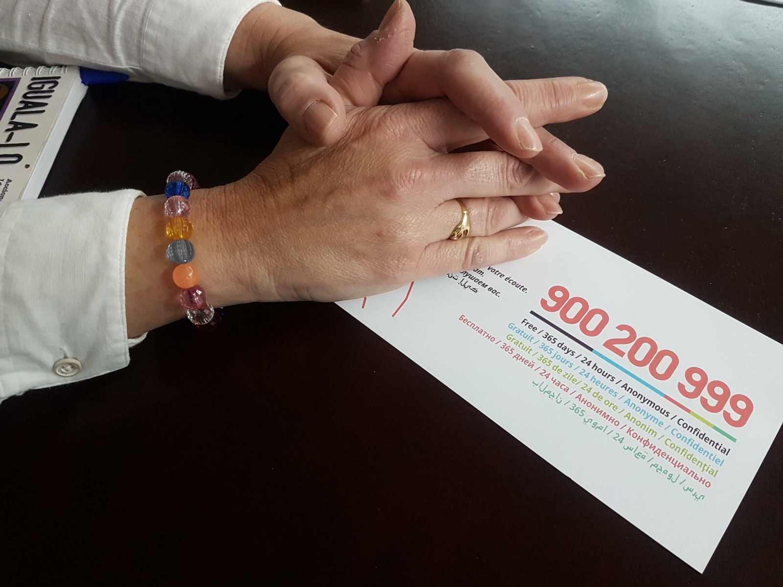 Una mujer que fue víctima de la violencia machista muestra el Teléfono de Información a la Mujer del IAM.