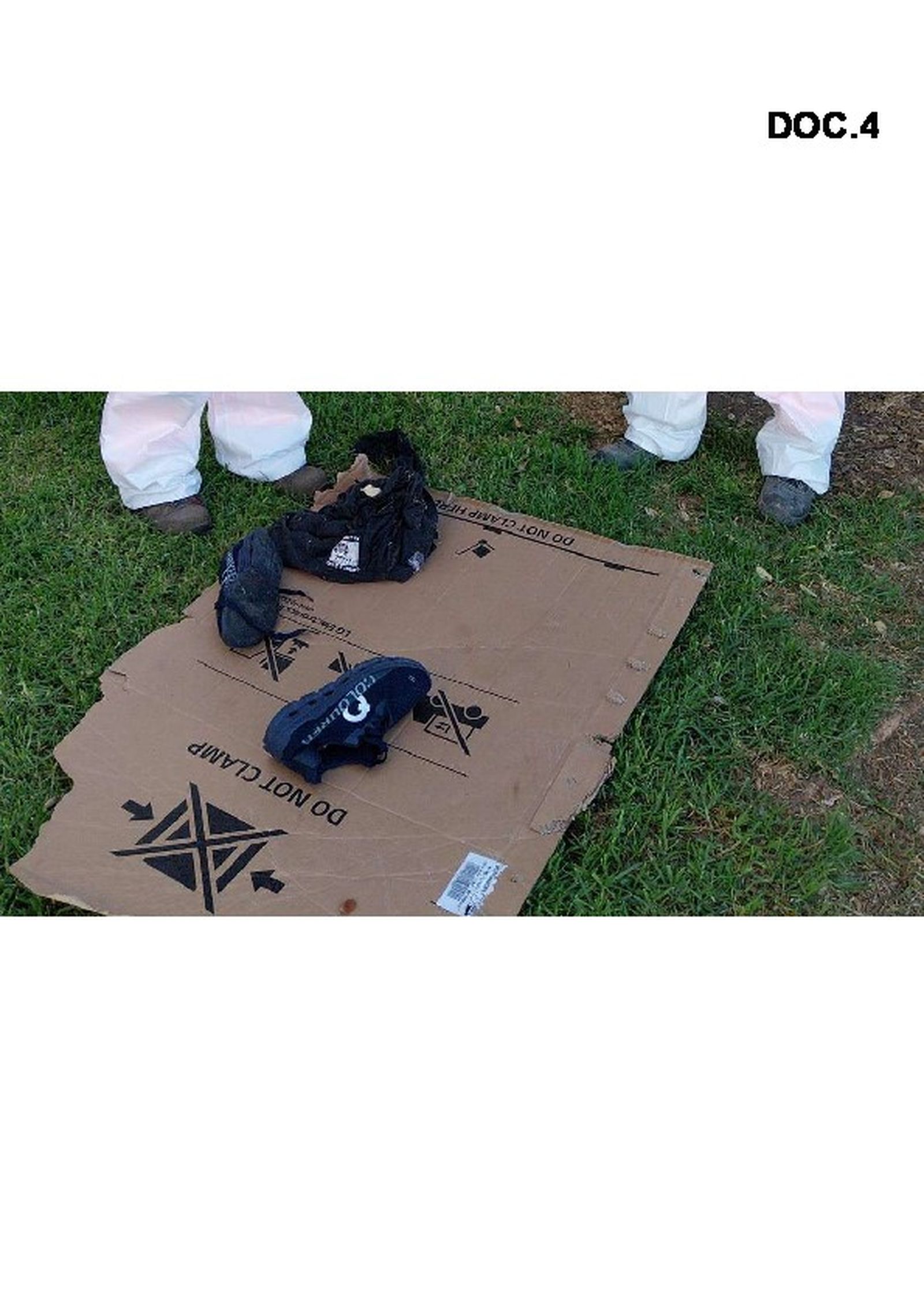 Par de zapatos y una prenda de ropa de una personas sin hogar en una zona verde.