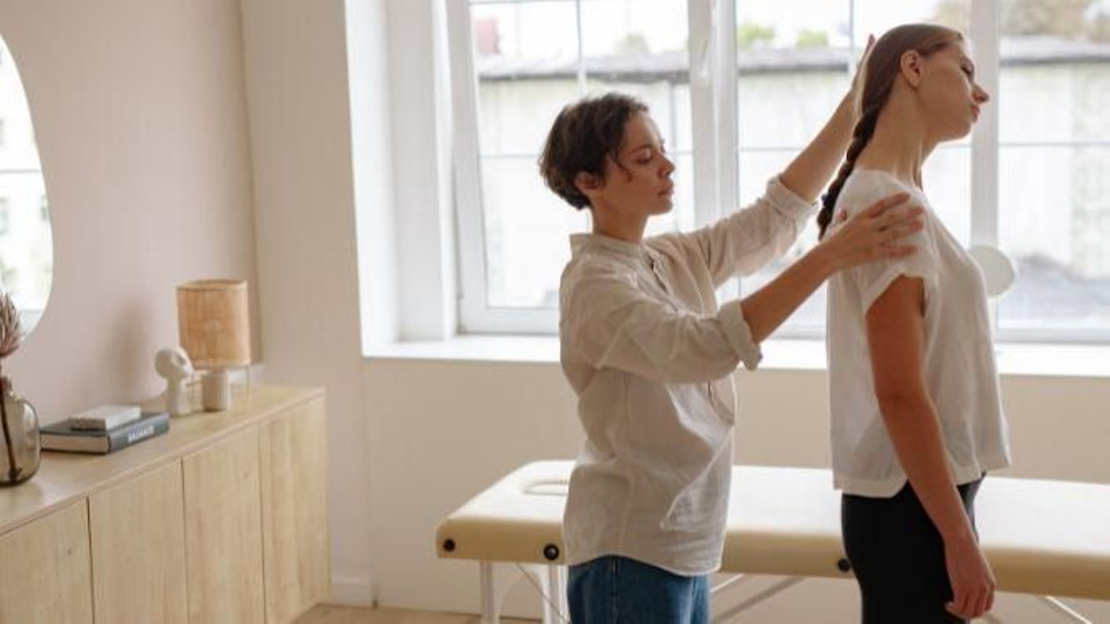 Fisioterapeuta realizando ejercicios de estiramiento con paciente con hombros caídos