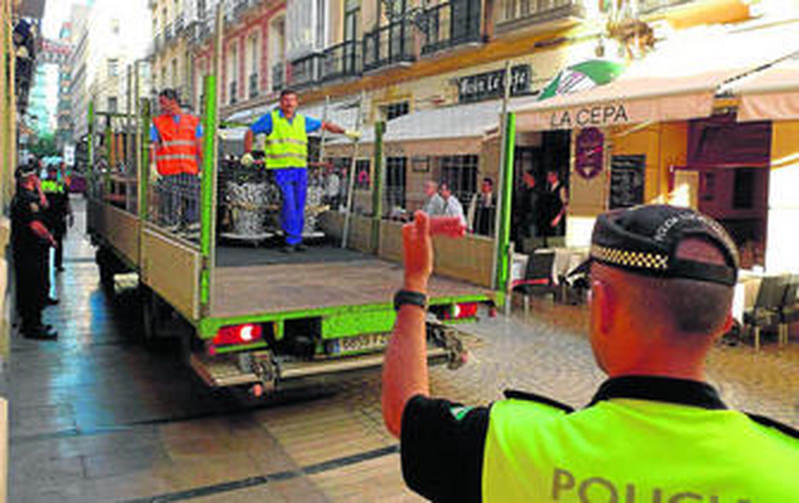 Un policía local dirige a uno de los camiones encargados de retirar ayer las mesas y sillas de las terrazas ilegales del centro.