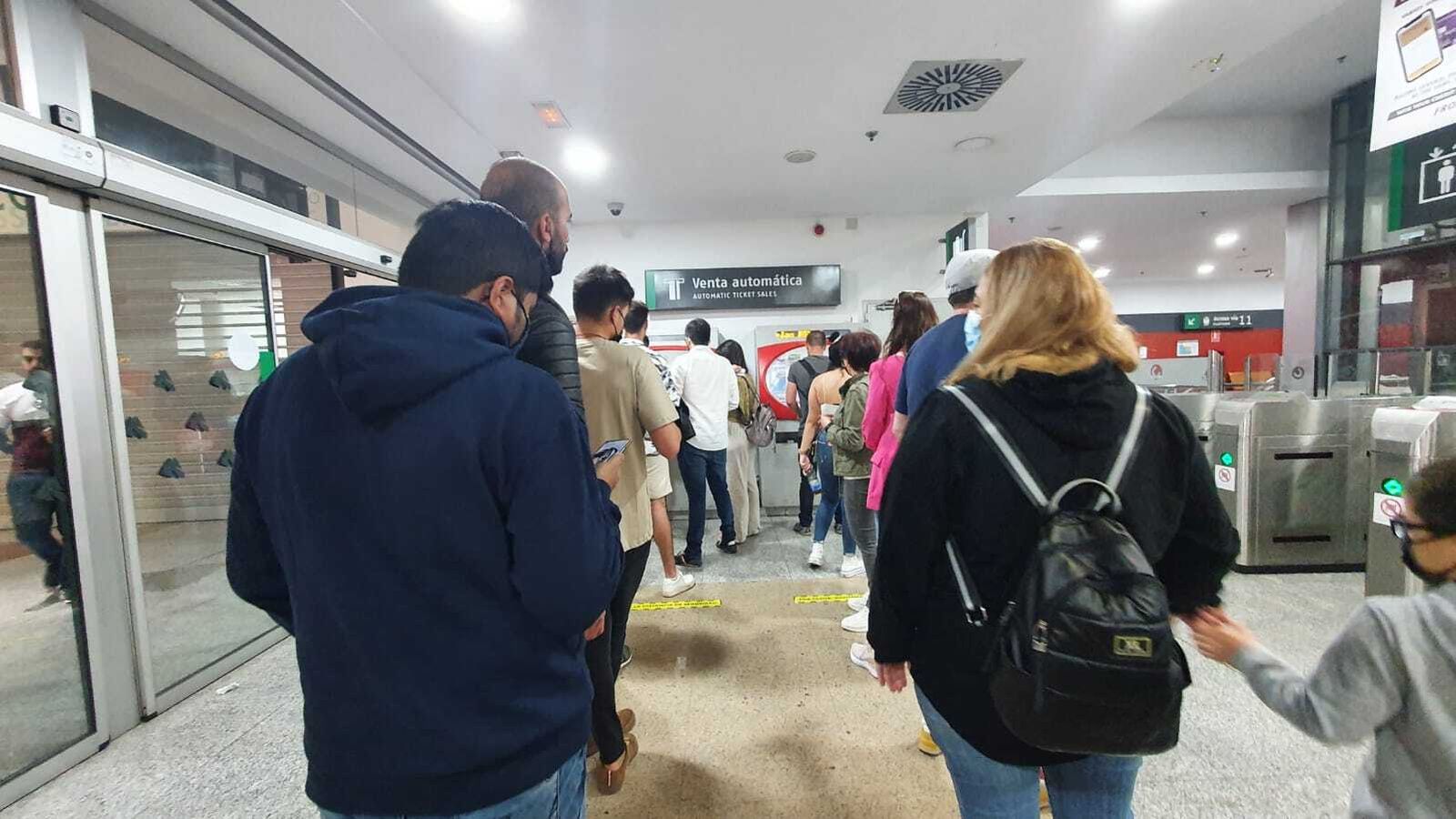 Personas esperan para sacar un ticket junto a los tornos del Cercanías.