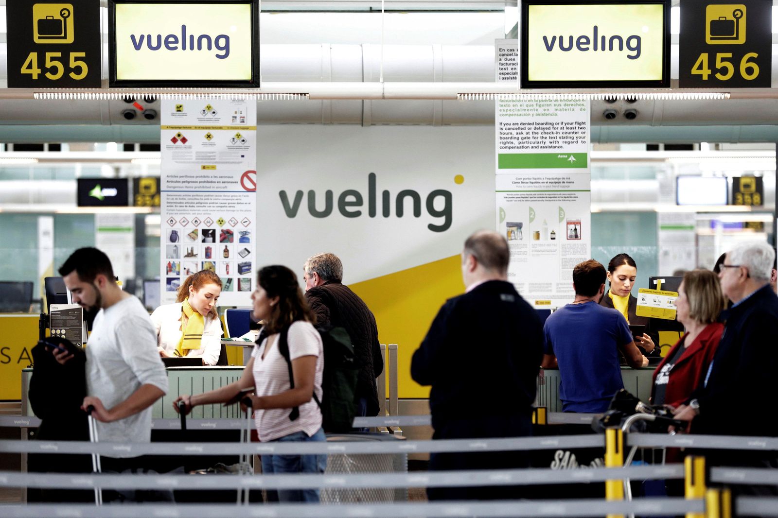 Un grupo de pasajeros ante un mostrador de facturacion de Vueling  en el Aeropuerto de Barcelona-El Prat.