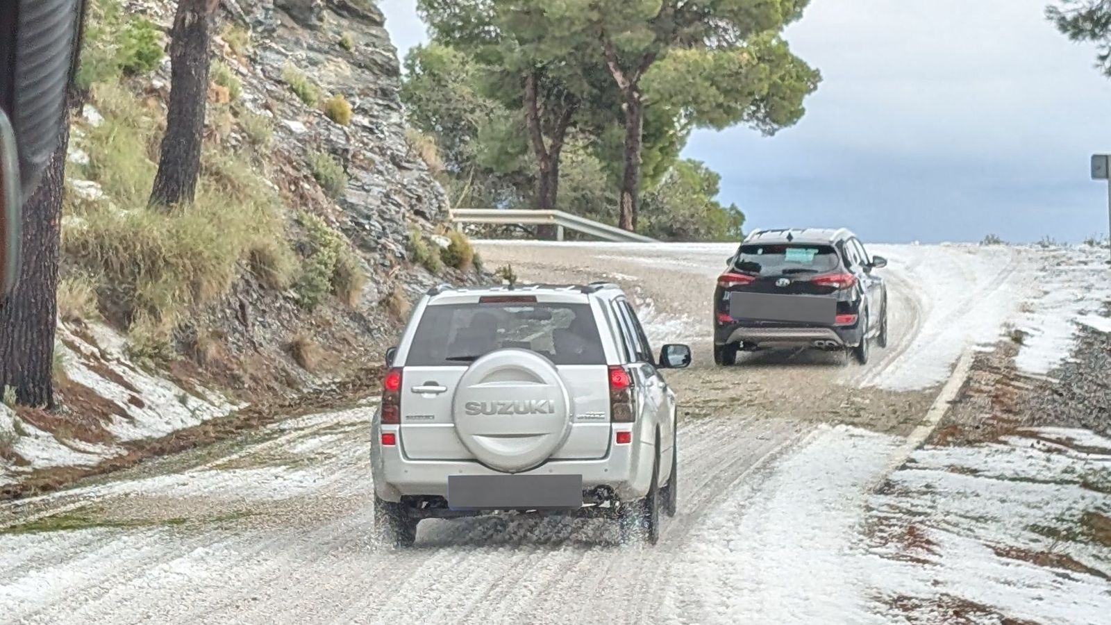 Coches circulan por la carretera GR-5207 cubierta de granizo