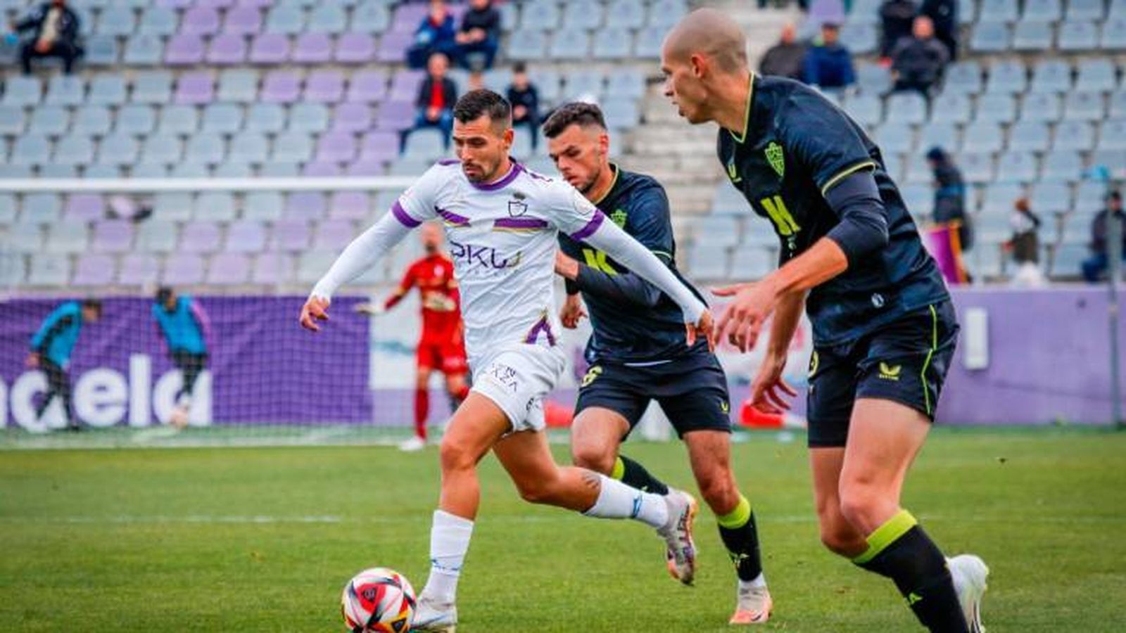Adri Paz conduce el balón ante dos rivales del filial almeriense en el partido disputado en La Victoria.