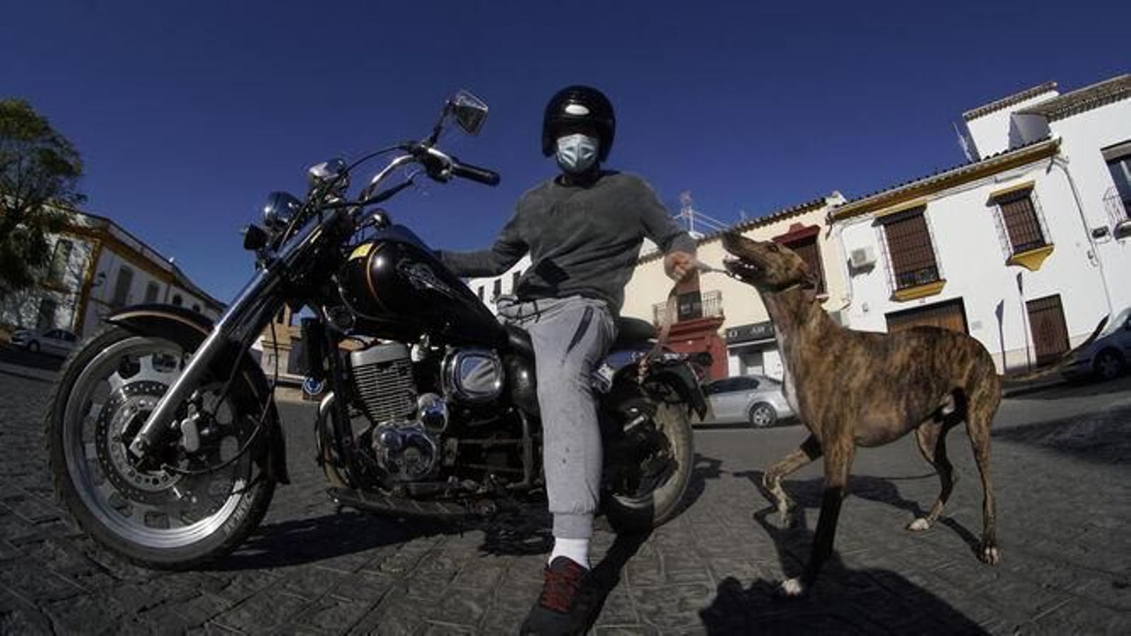 Un motorista, con su vehículo, casco y mascarilla