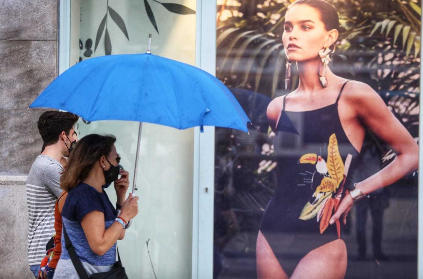 Dos personas, con paraguas y mascarilla, en el centro de Málaga.