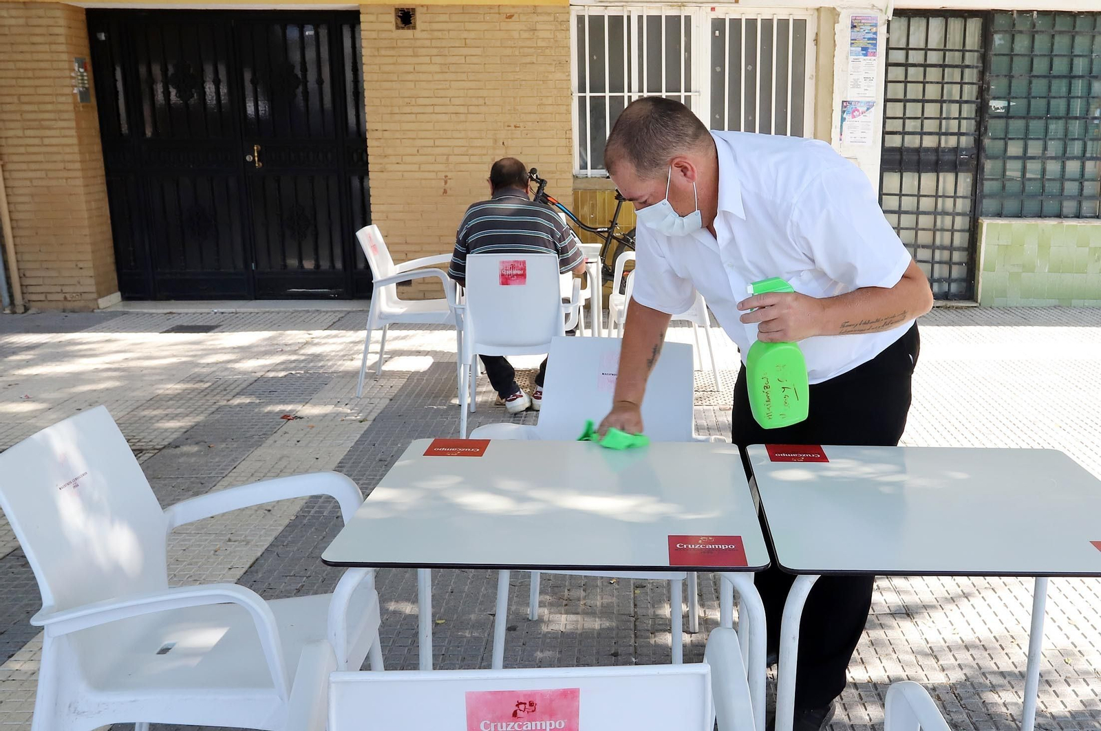 Un camarero limpia la mesa de una terraza.