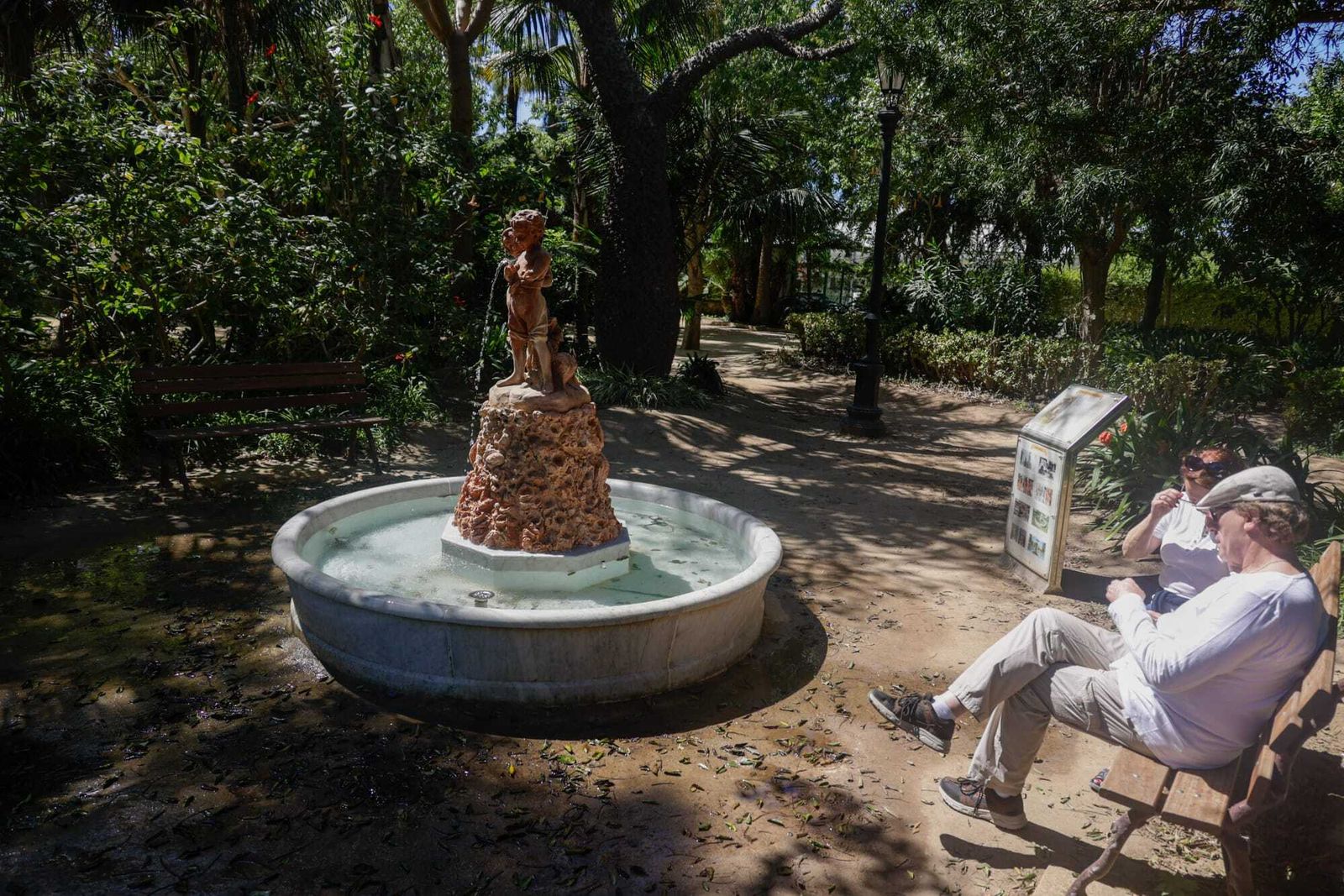 Dos turistas sentados frente a la fuente de Los Niños del Paraguas.