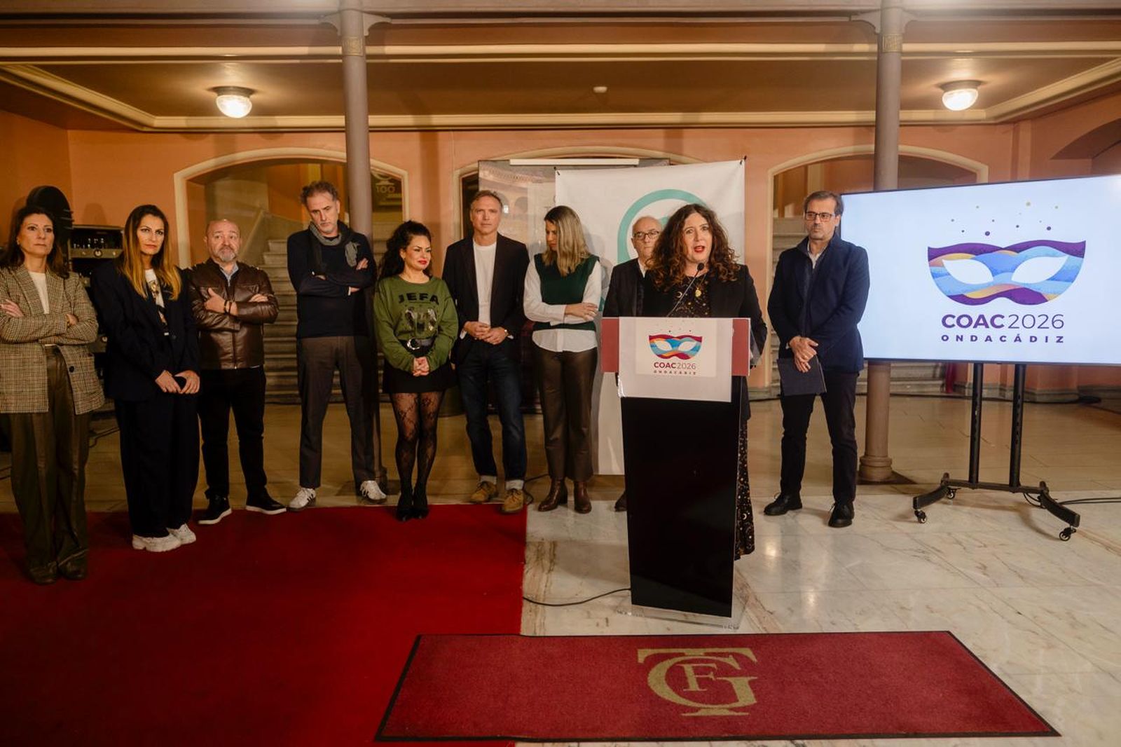 Raquel Vázquez presenta la cobertura de Onda Cádiz con el equipo de profesionales detrás en el hall del Teatro Falla.