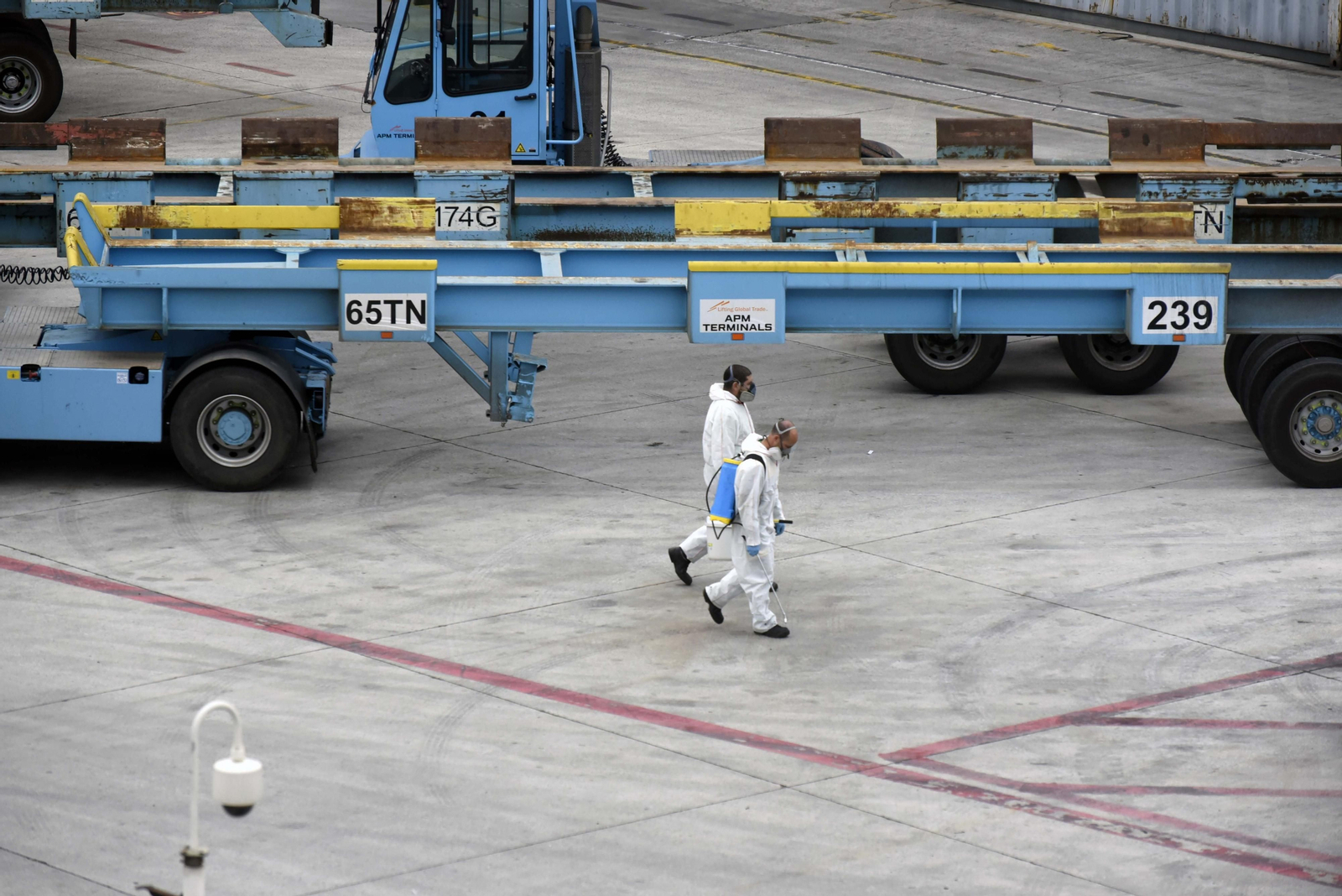 Dos personas encargadas de la desinfección de maquinaria caminan por APM Terminals Algeciras.
