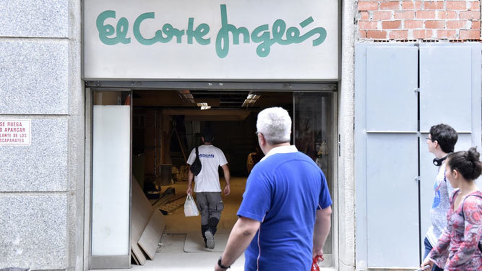 Tres personas observan las obras que los grandes almacenes realizan en la zona que linda con la calle Tarifa.