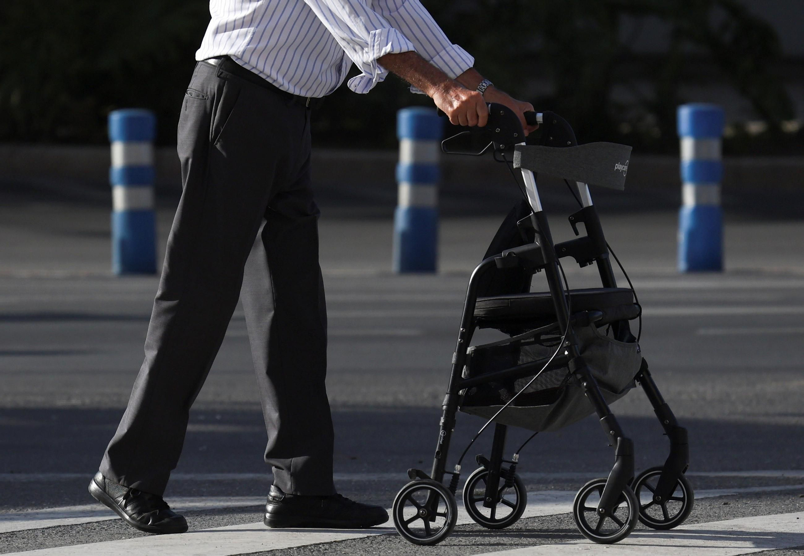 Un hombre se ayuda de una silla con ruedas en Málaga.