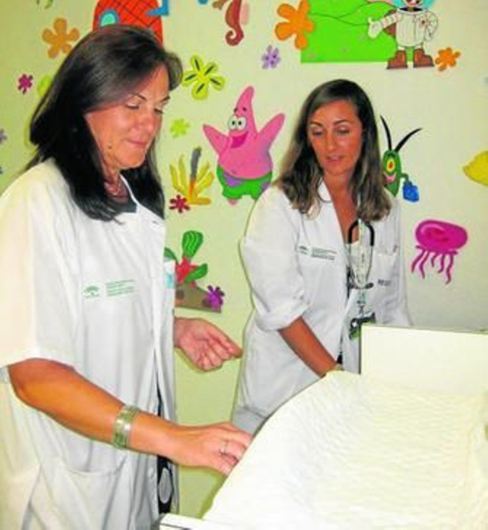 Yolanda Ramón (izquierda) y María José Peláez, enfermera y pediatra de HADO, preparan la balanza para pesar a un niño.