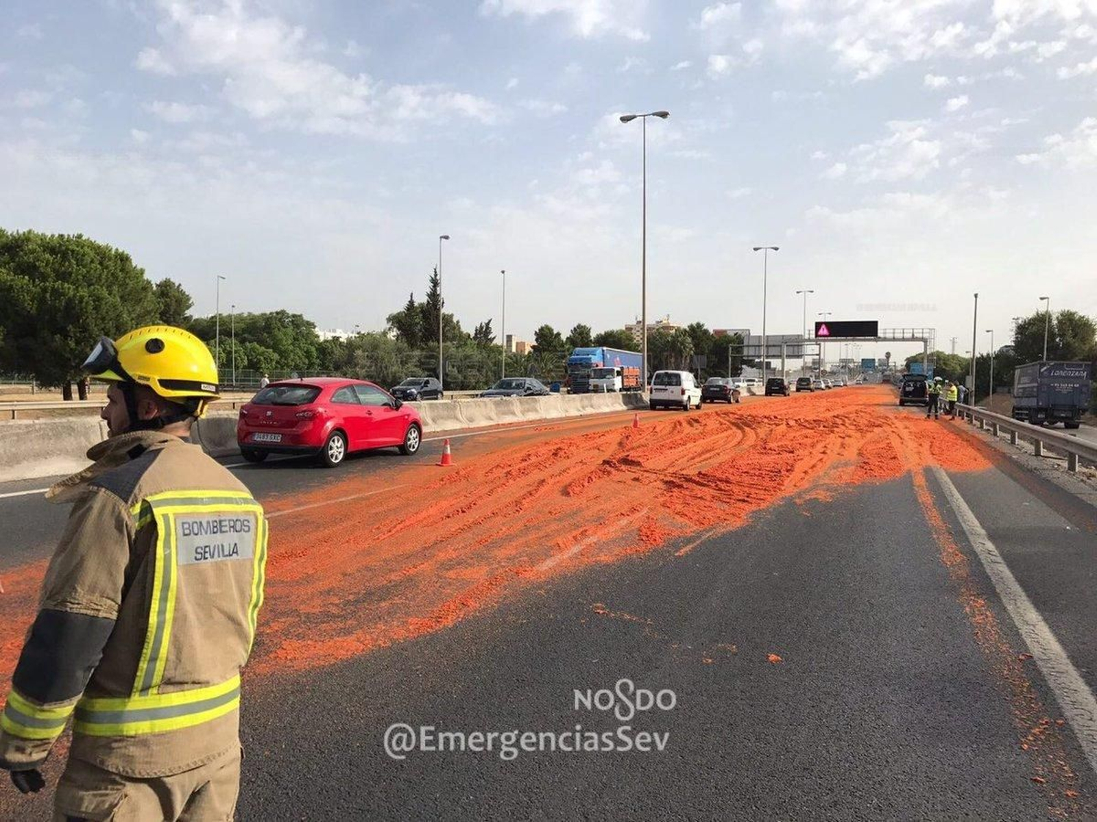 Un tramo de la SE-30 cubierto de tomate triturado al volcarse la carga de un camión.