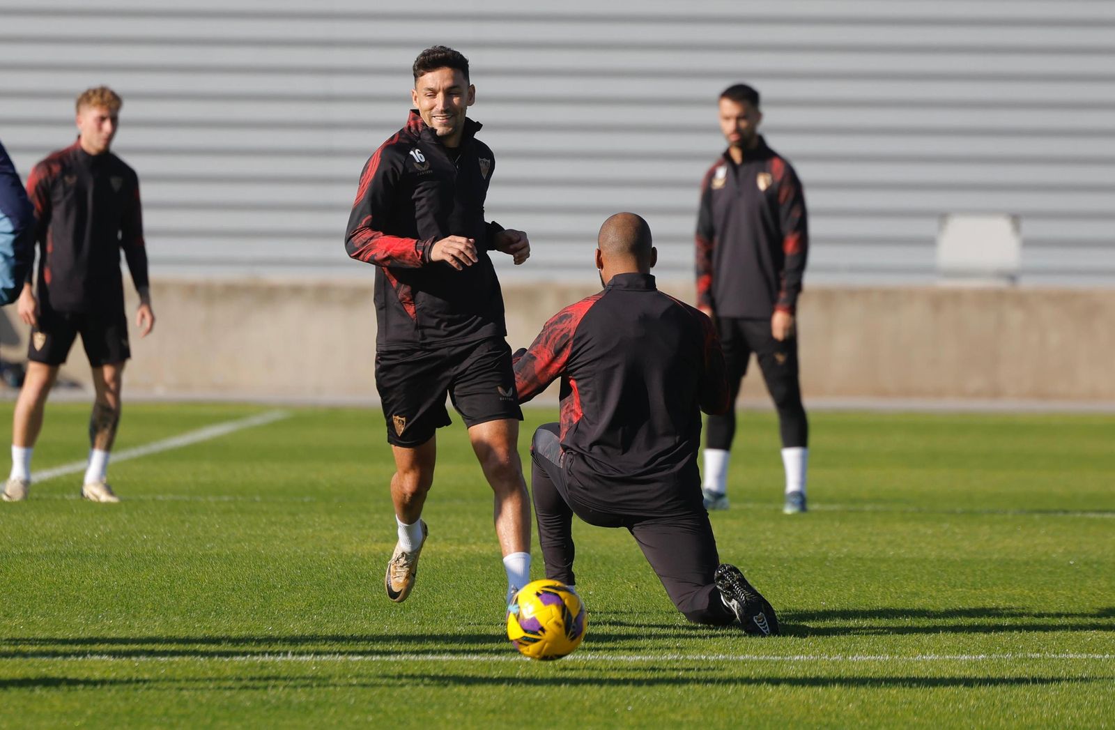 Jesús Navas sonríe ante Marcao, genuflexo para hacerle una reverencia en el entrenamiento.