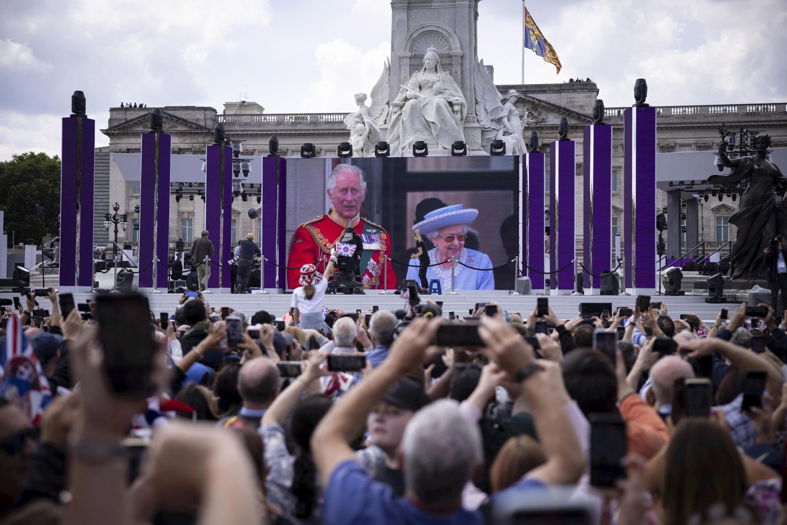Los londinenses siguen en una pantalla el saludo de la reina y el príncipe de Gales