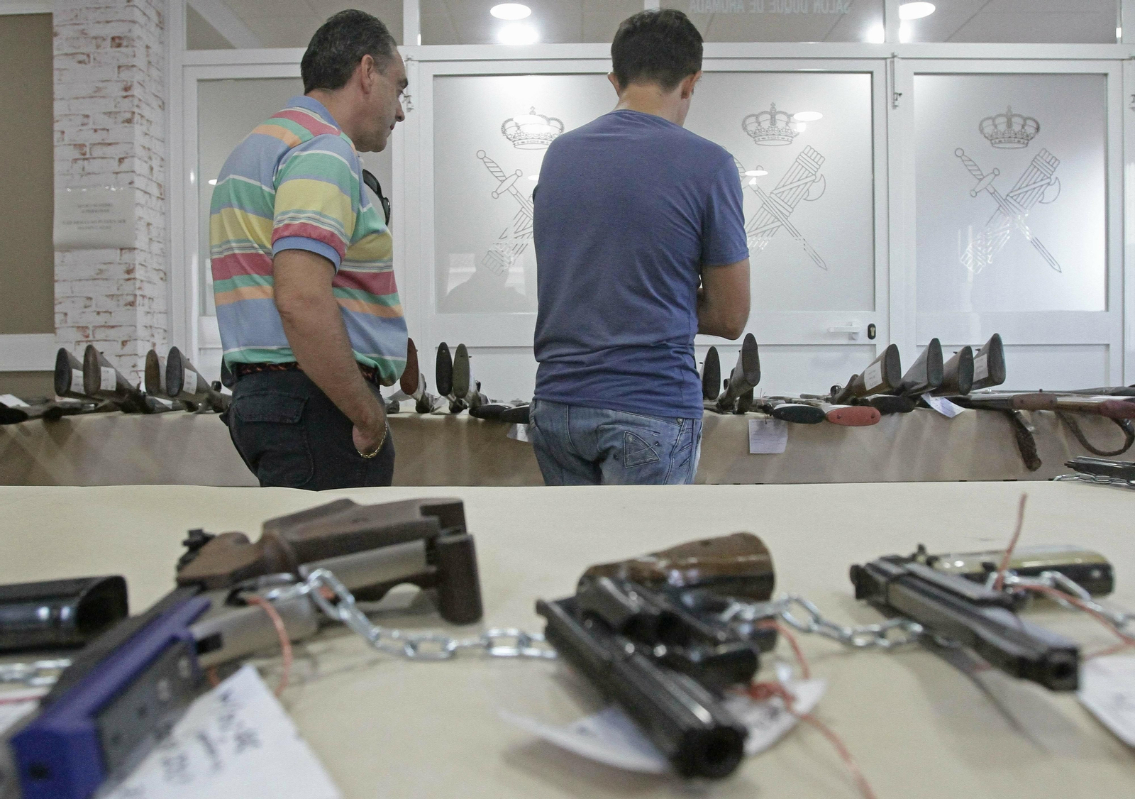 Dos personas observan los lotes en una subasta anterior.