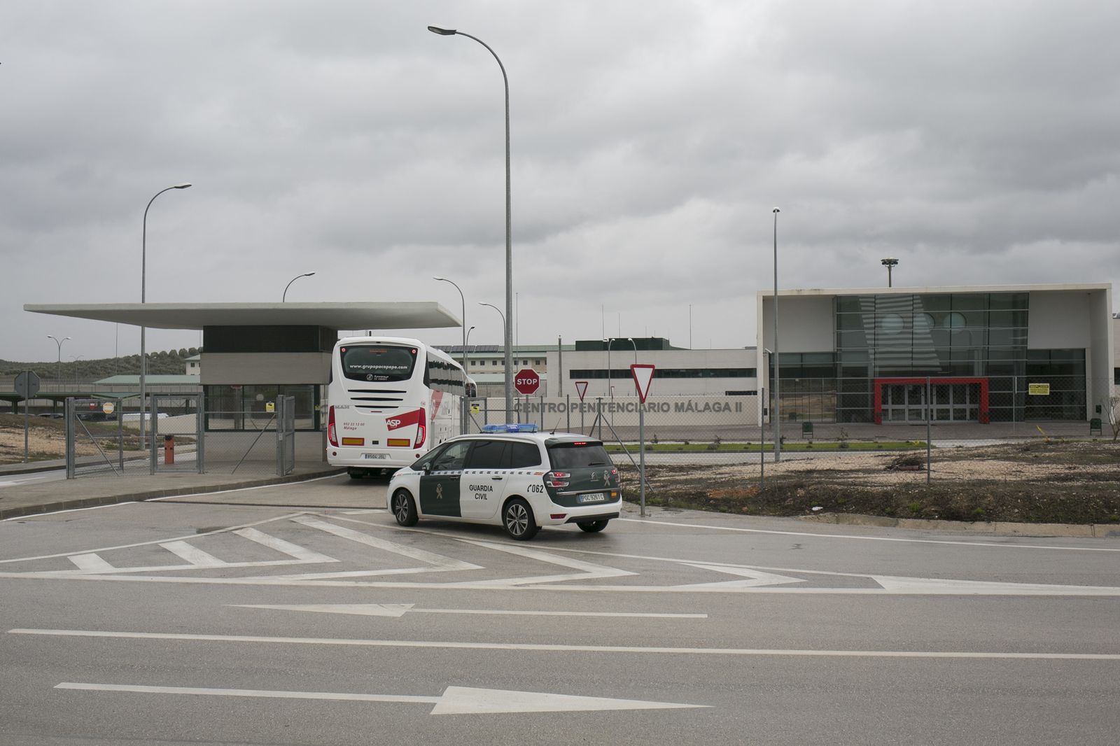 Un autobús y un coche de la Guardia Civil entrando en la cárcel de Archidona.