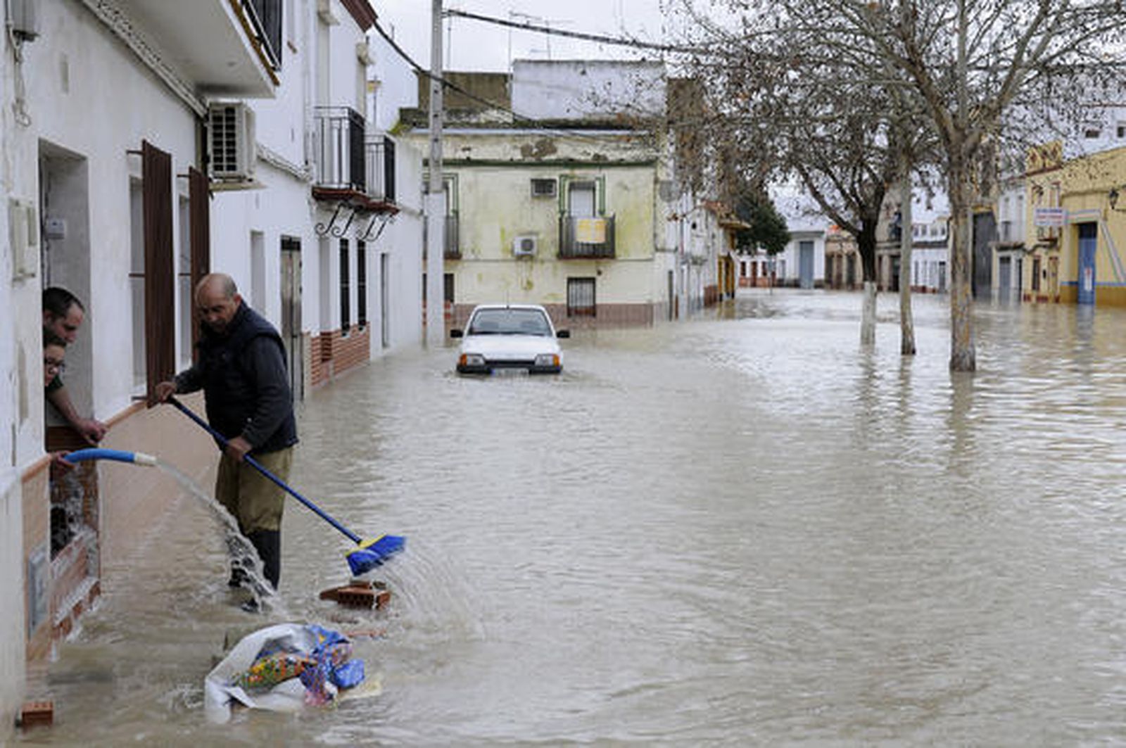 Varios vecinos de Lora del Río usan mangueras y escobas para achicar el agua que inunda sus casas. 

Foto: Juan Carlos Vázquez