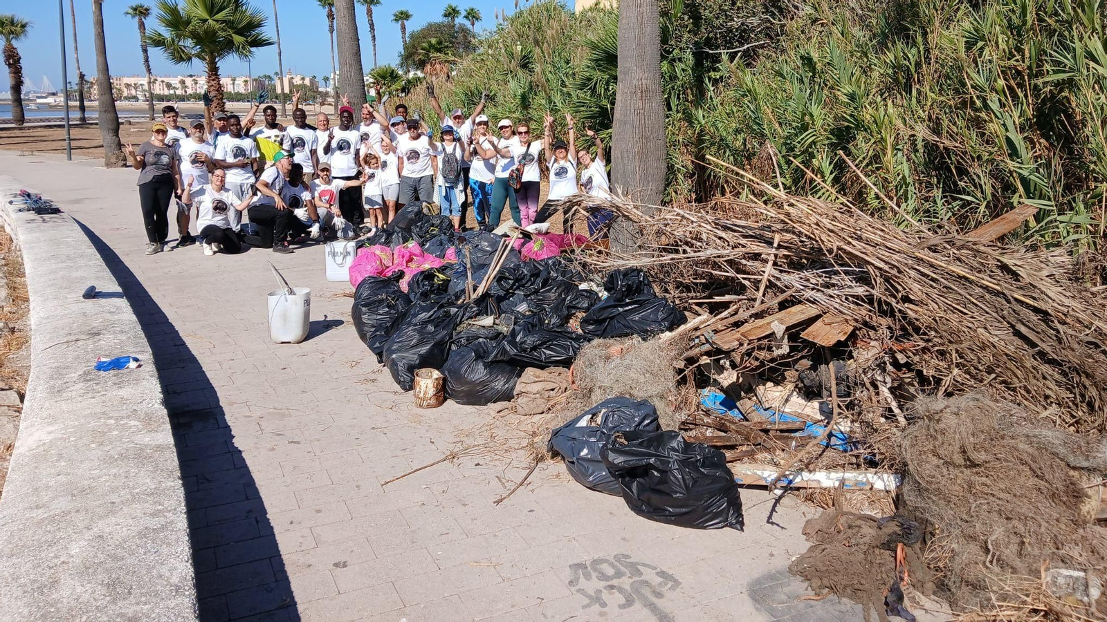 Voluntarios que participaron en la limpieza junto a la basura retirada