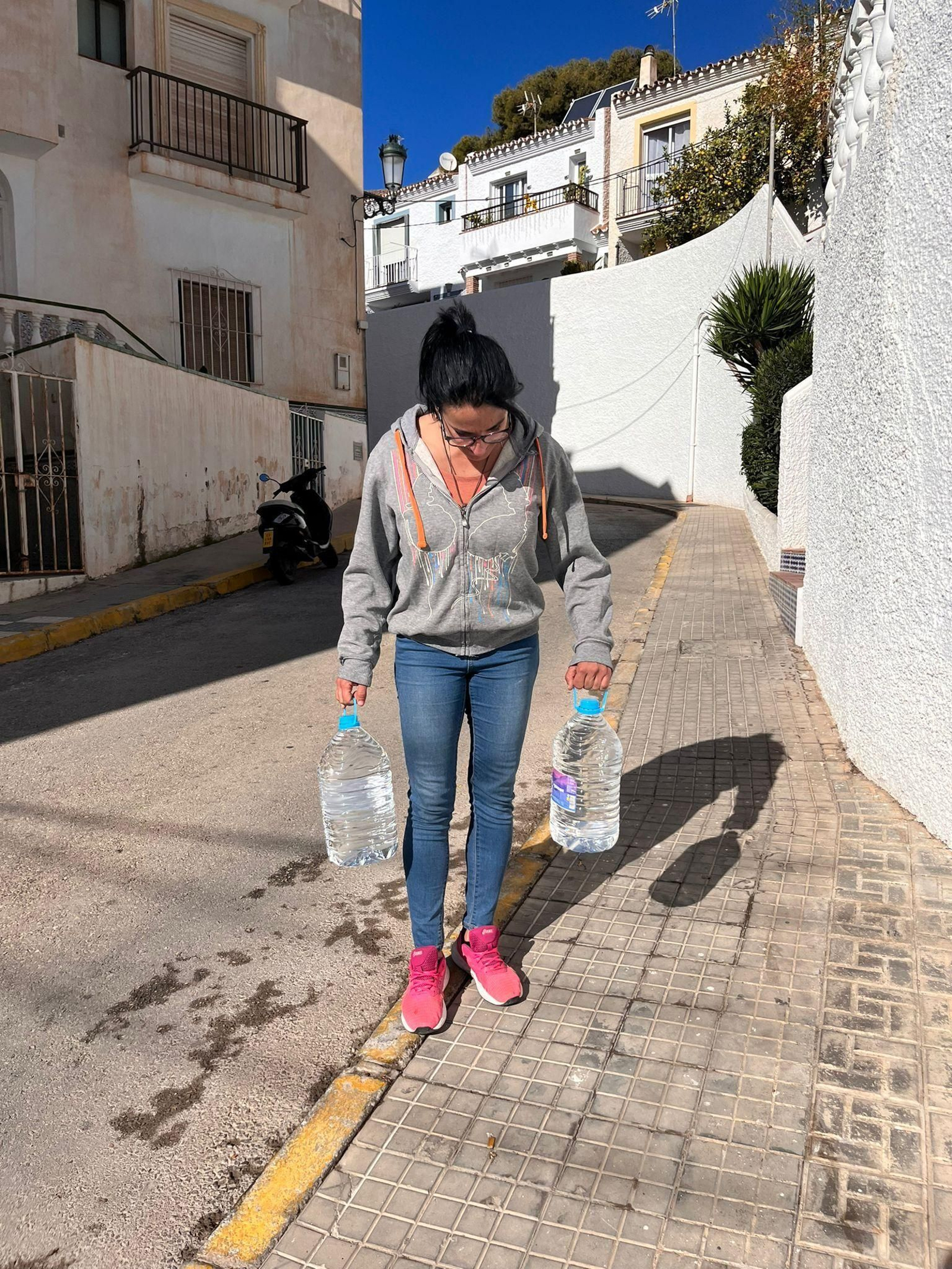 Una vecina de Maro cogiendo dos garrafas de agua Una vecina de Maro cogiendo dos garrafas de agua