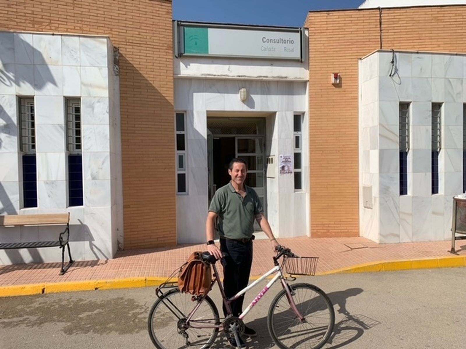 Ángel López Hernánz delante del consultorio donde trabaja junto a su bicicleta.