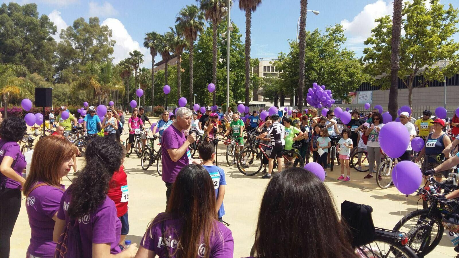 Ciudadanos montados en bicicleta y con globos morados contra la violencia de género.