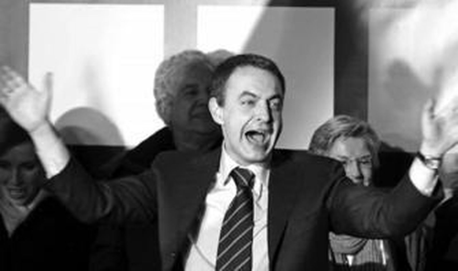 Zapatero hace un gesto de alegría al saludar a sus partidarios reunidos frente a la sede socialista de la calle Ferraz.