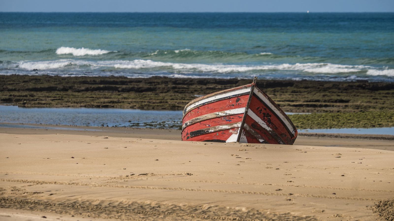 Una patera como la que llegó ayer a Huelva varada en la playa.