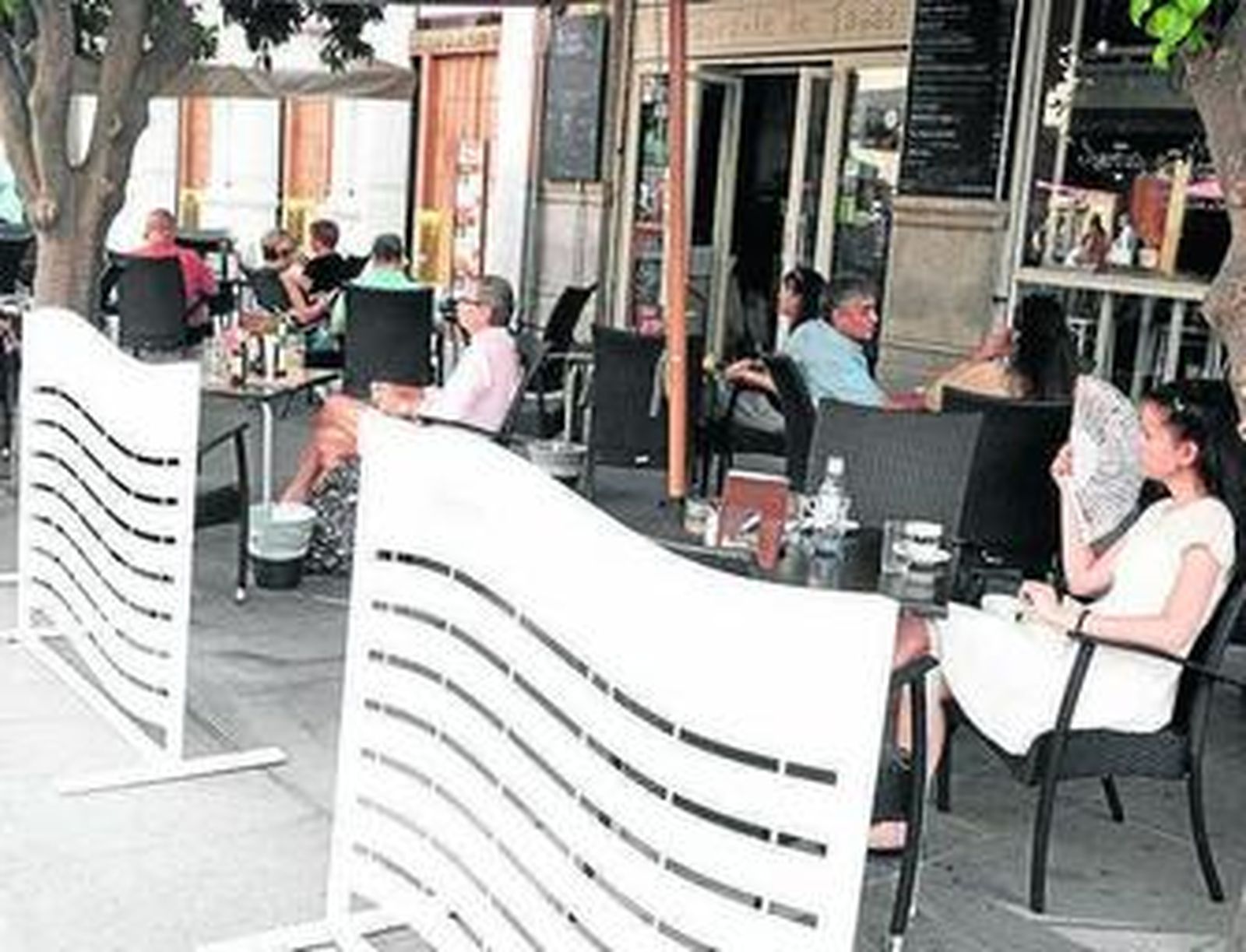 Clientes sentados en el velador de un negocio de la Avenida de la Constitución.