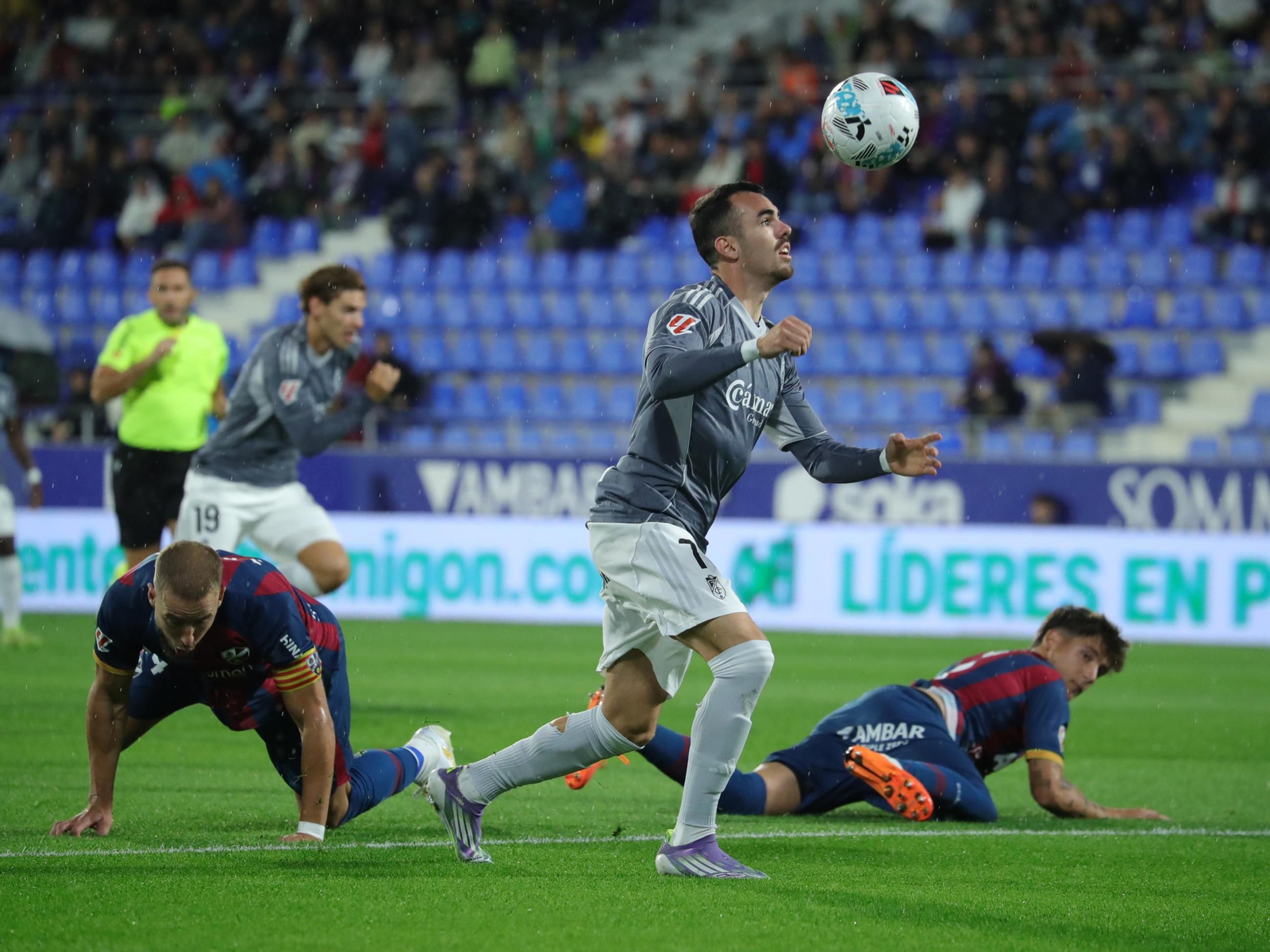 Álex Sola se prepara para rematar ante dos jugadores del Huesca
