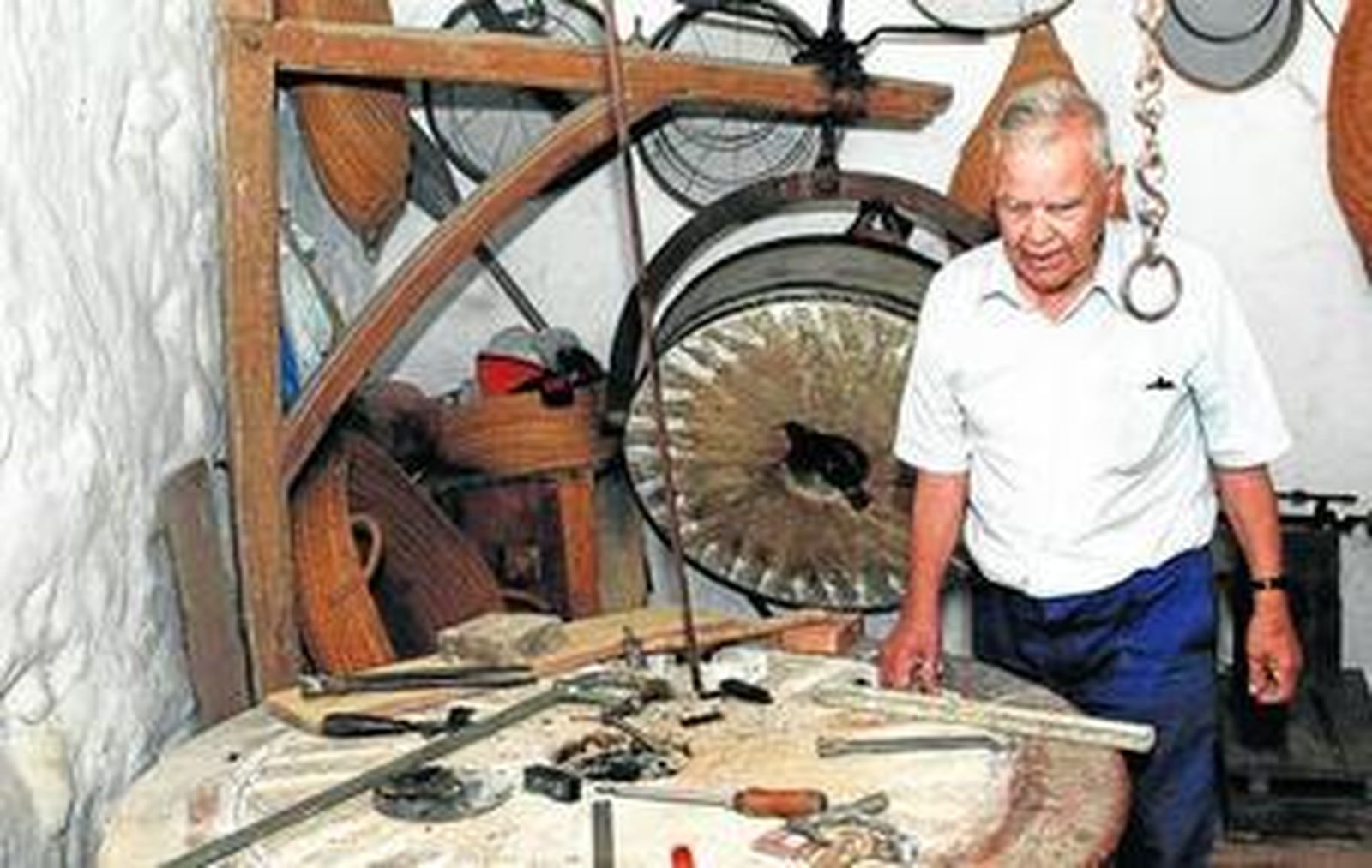 Juan González en su taller, ayer por la mañana, con la piedra del molino a sus espaldas.