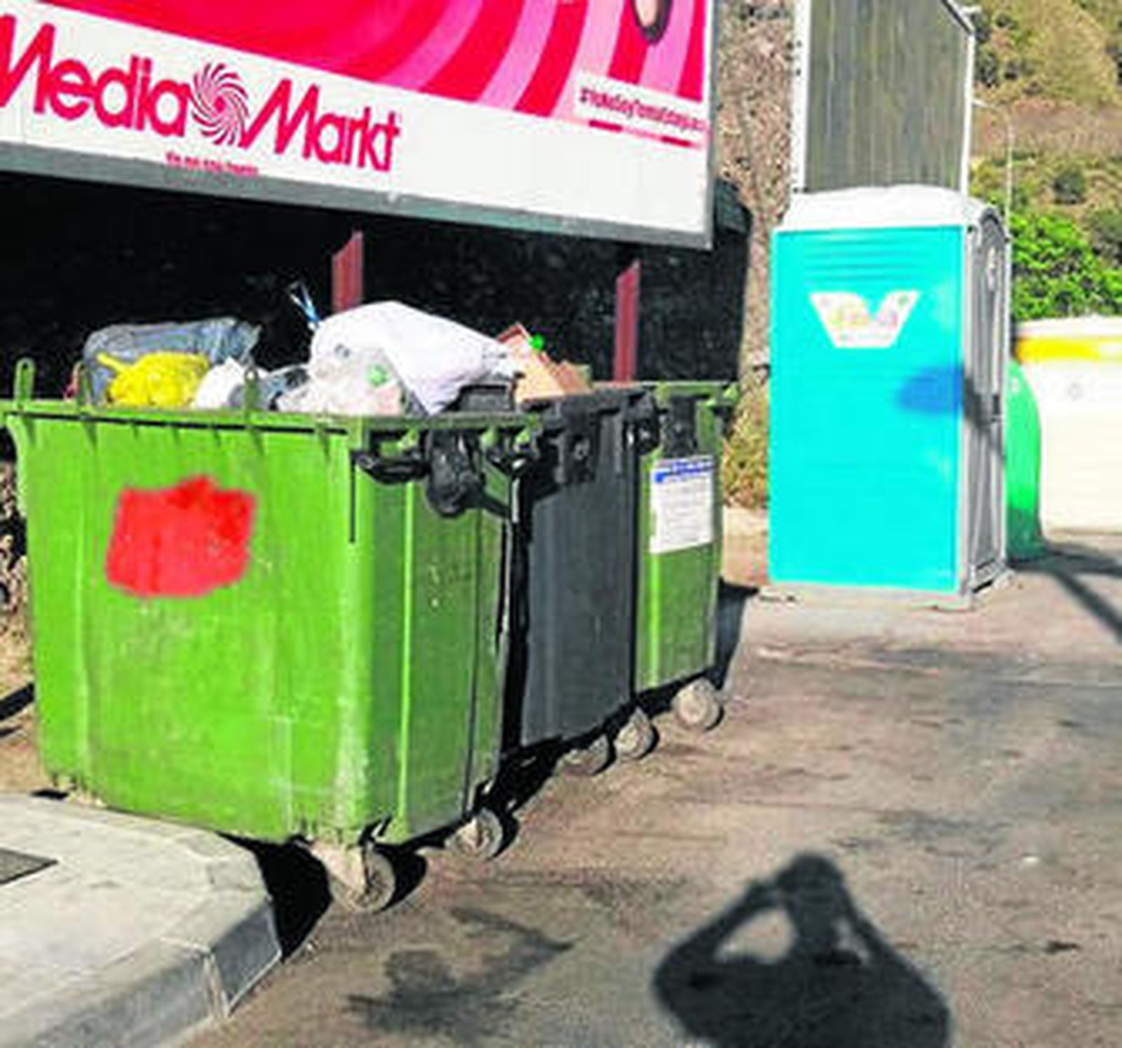 Imagen del baño móvil, situado entre contenedores de basura.