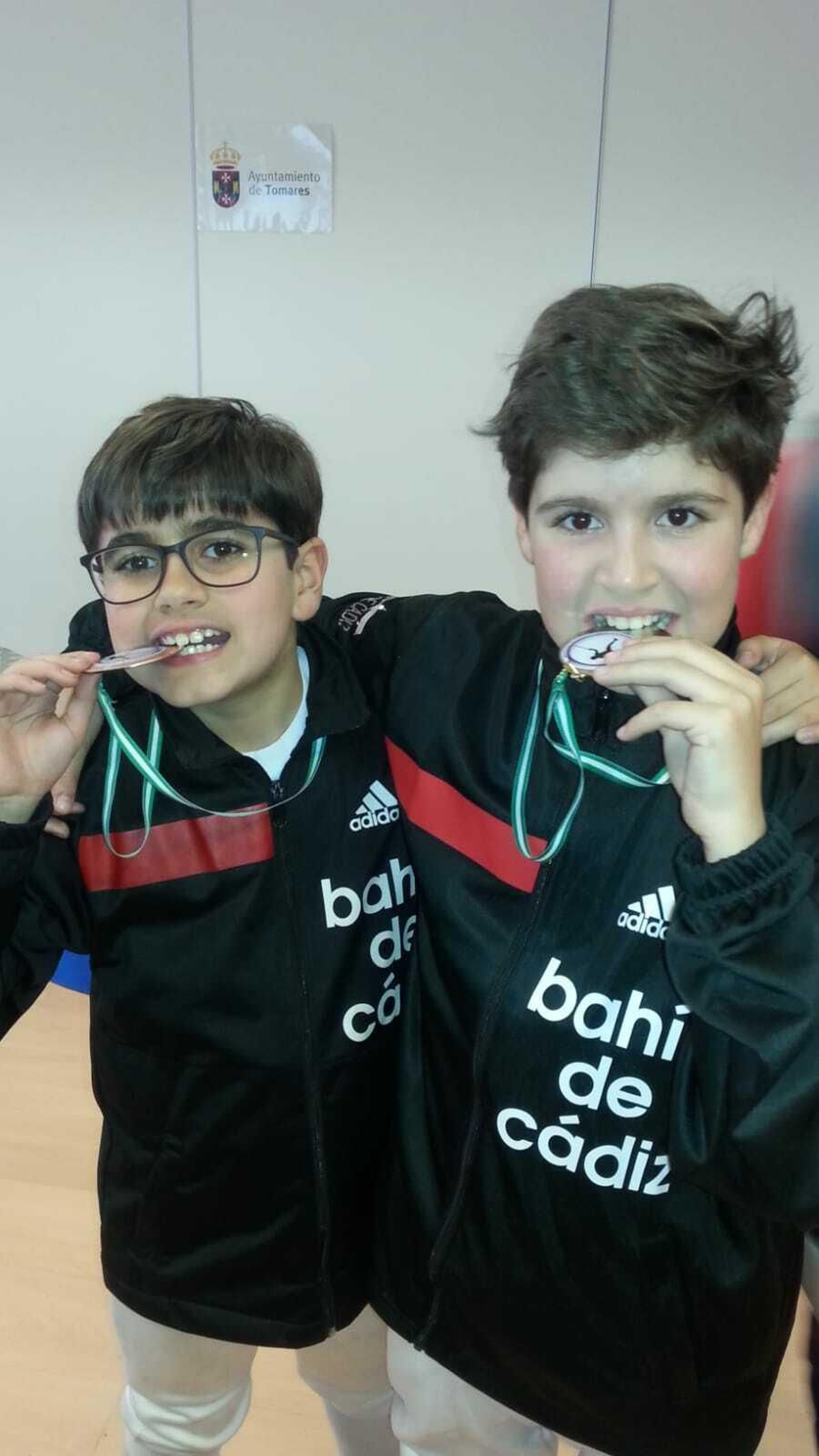 Los primos Rubén y Darío Marqués muerden las medallas que lograron en Tomares.
