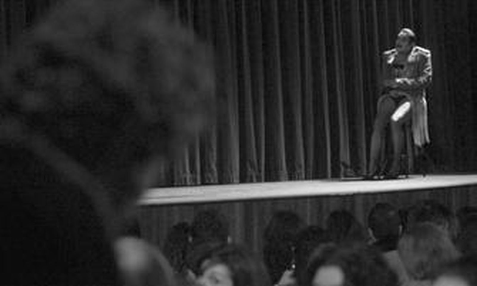 El maestro de ceremonias, sobre el escenario, habla con otro de los personajes que se marcha del patio de butacas.