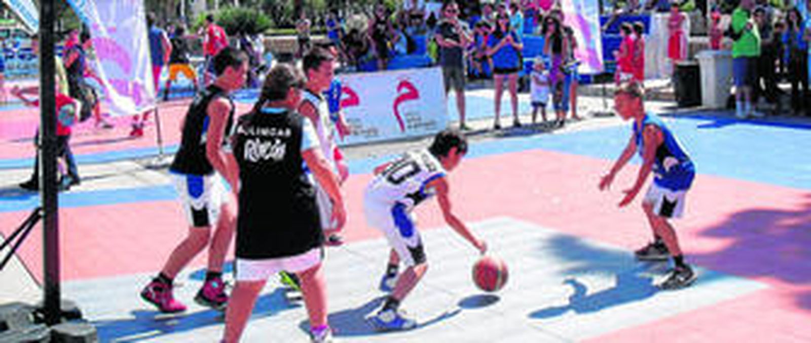 1. Uno de los participantes del torneo bota la pelota ante la defensa del equipo rival. 2. Cartel promocional del acto que tuvo lugar a lo largo del día de ayer. 3. Uno de los participantes tira a canasta ante la defensa de un jugador rival. 4. Panorámica de las instalaciones en las que tuvieron lugar los diferentes encuentros del torneo.