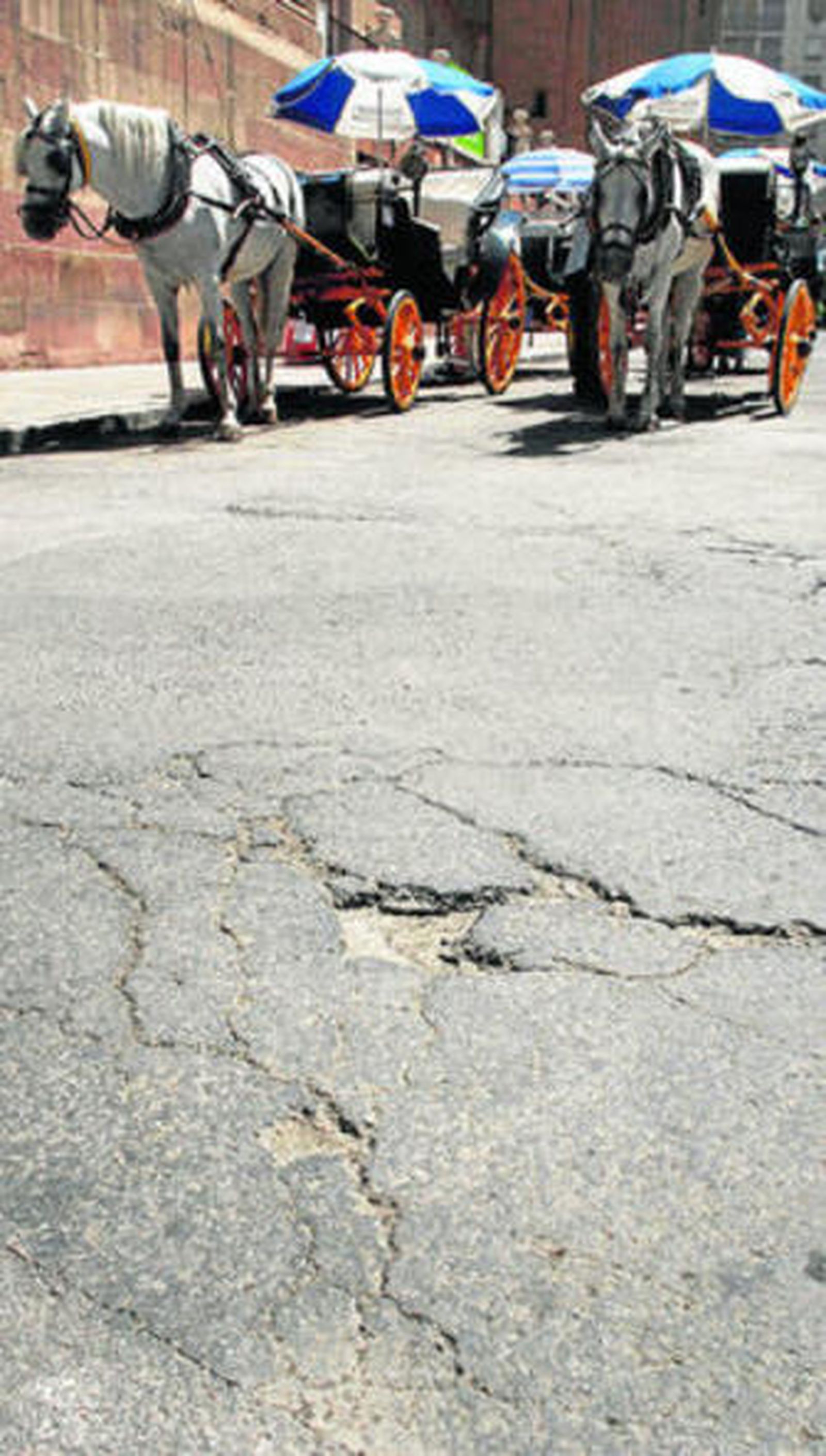 Dos coches de caballos pasan por la calle Molina Lario.