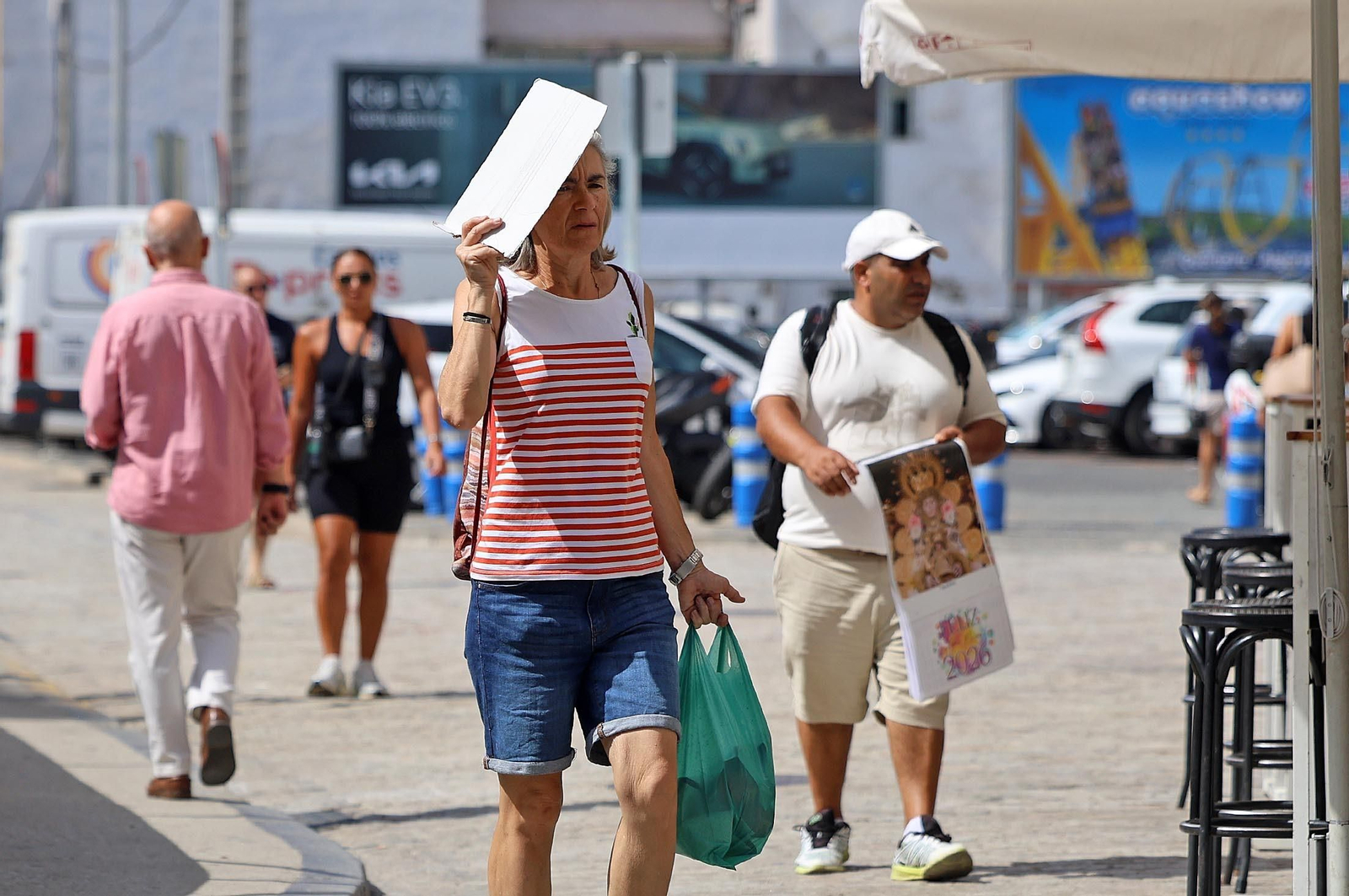 Una mujer pasea por Huelva capital y se resguarda del calor.