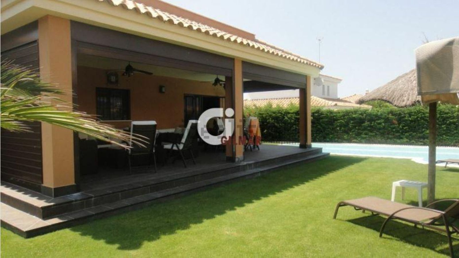 El porche y el jardín de este chalet en Roche.