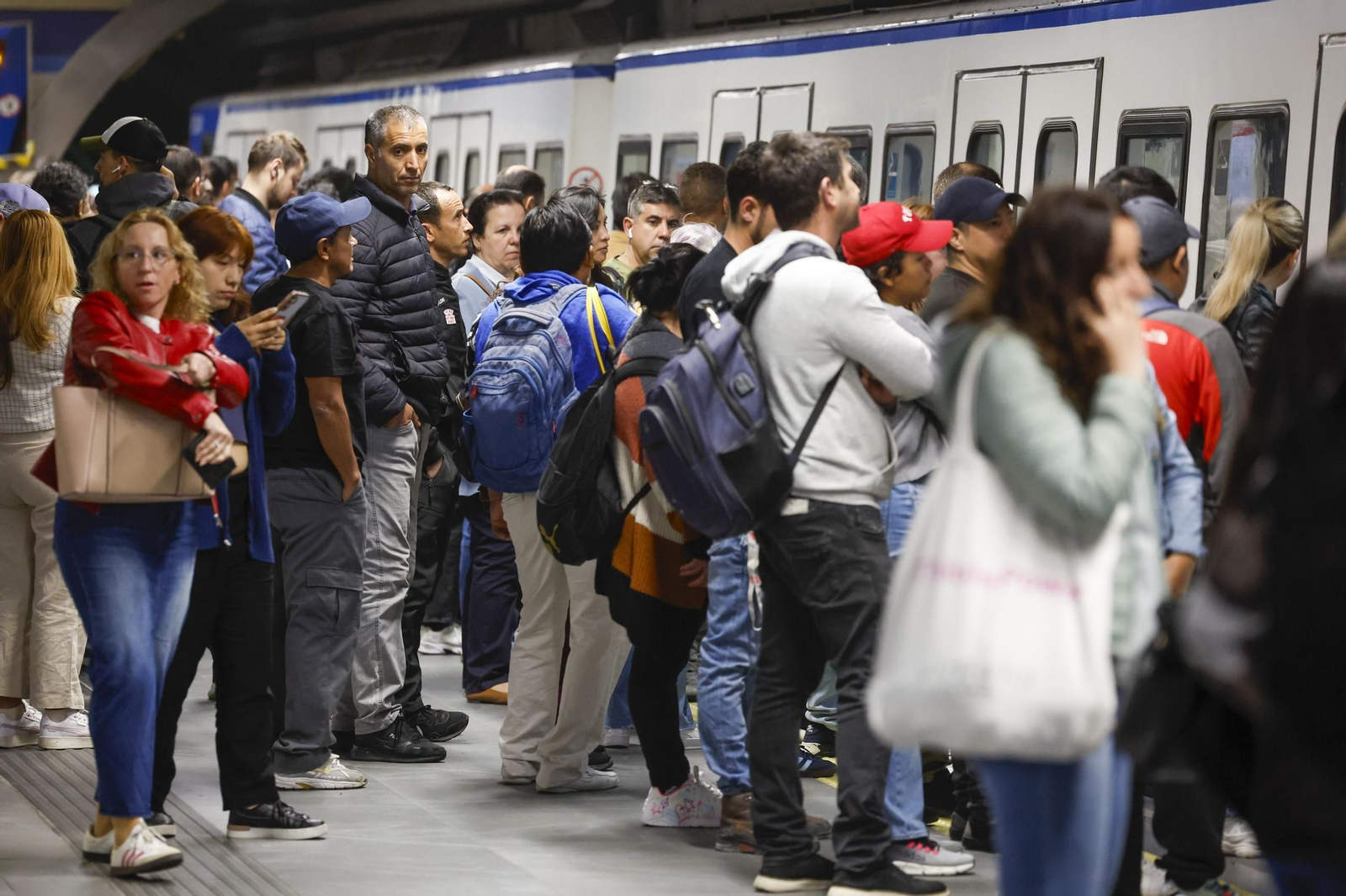 Usuarios del transporte público se agolpan ante las puertas de los vagones del metro de Madrid.