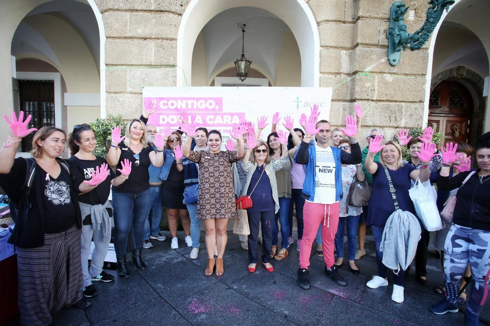 Personas con las palmas de las manos en rosa apoyando la campaña de la AECC en la plaza de San Juan de Dios.