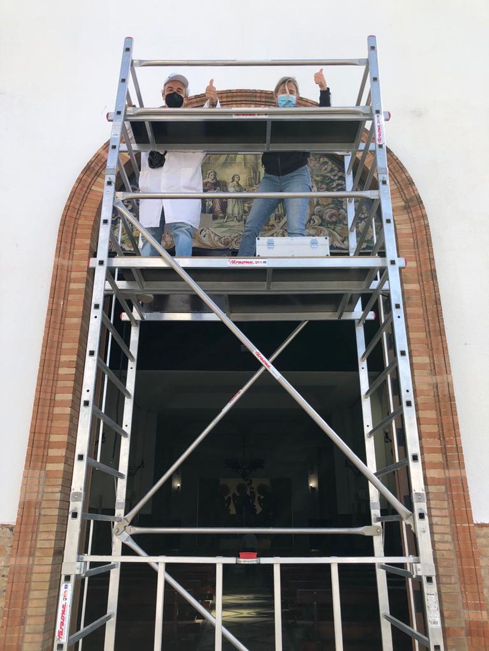 Los restauradores José Ramón Pizarro y Carmen Riego inspeccionan el retablo en un andamio.