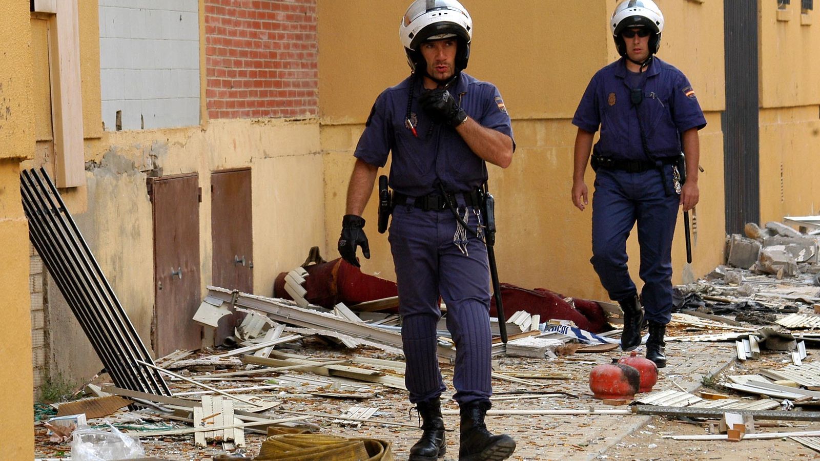 Dos policías nacionales caminan entre los restos del bloque tras la deflagración.