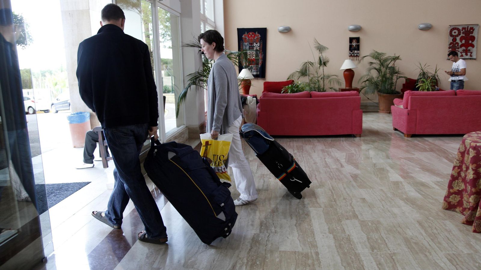 Dos turistas abandonan un hotel.