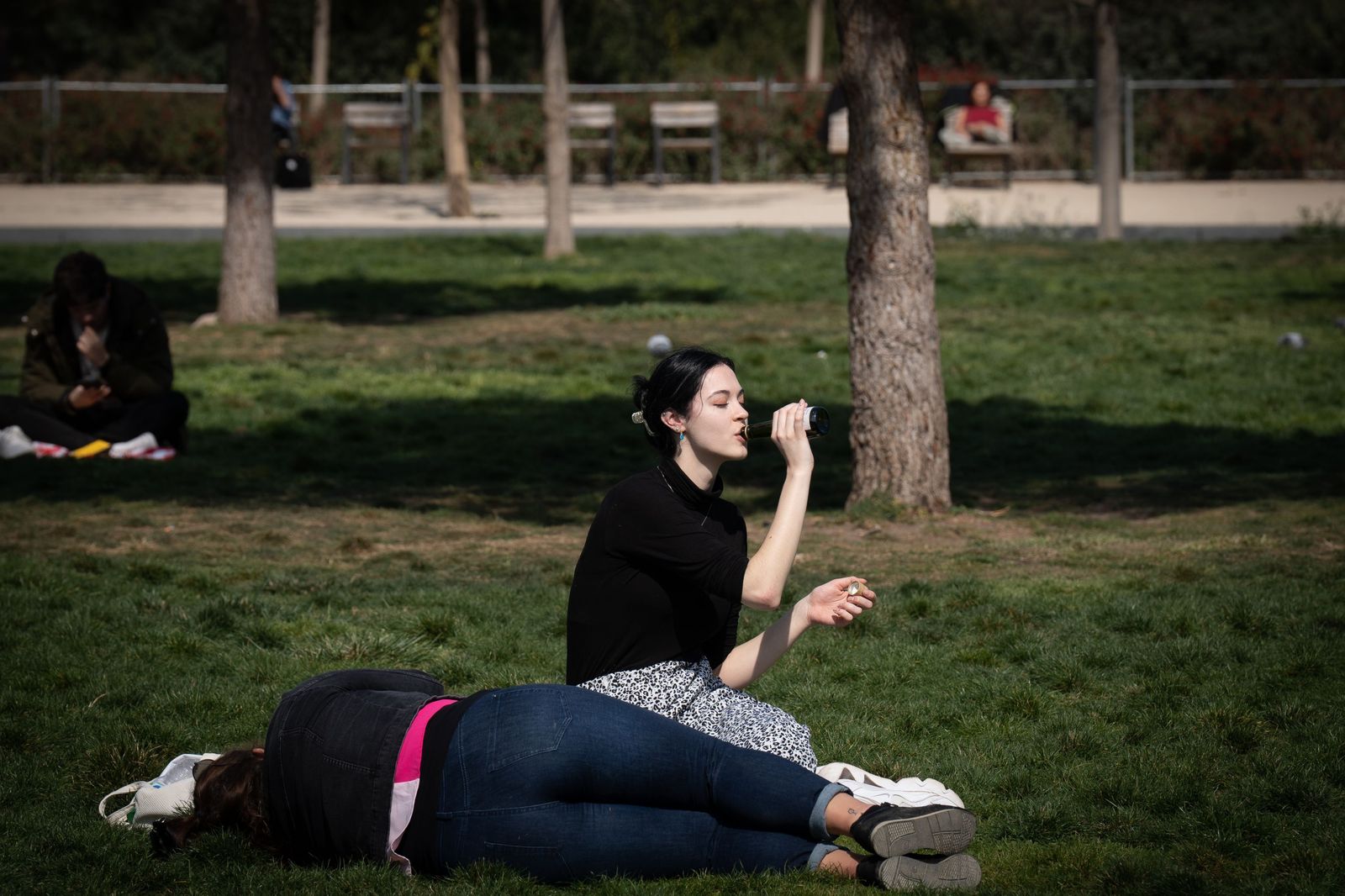 Jóvenes tomando el sol en un parque durante un mediodía de invierno.