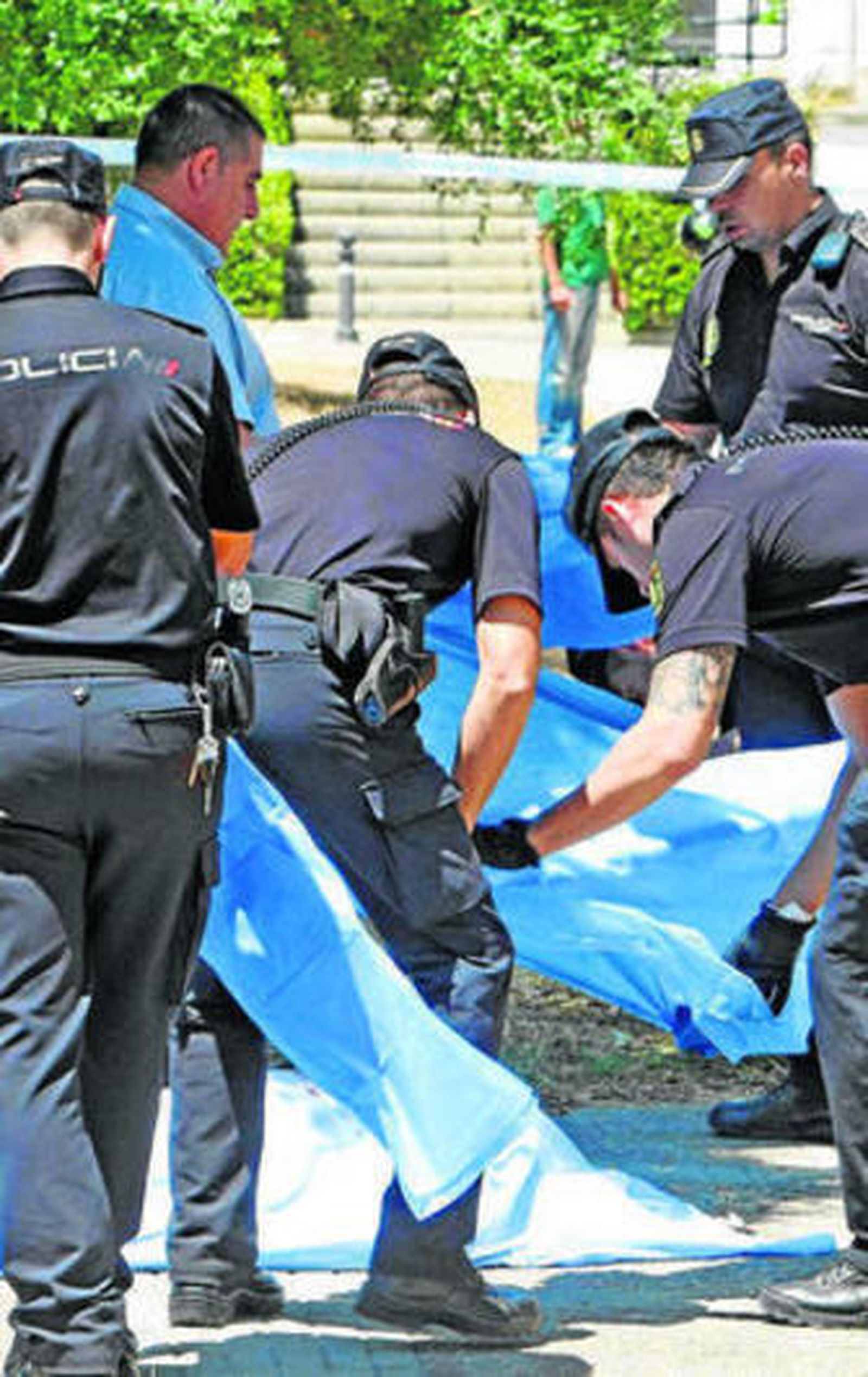 Miembros de la policía cubren el cadáver de la víctima.